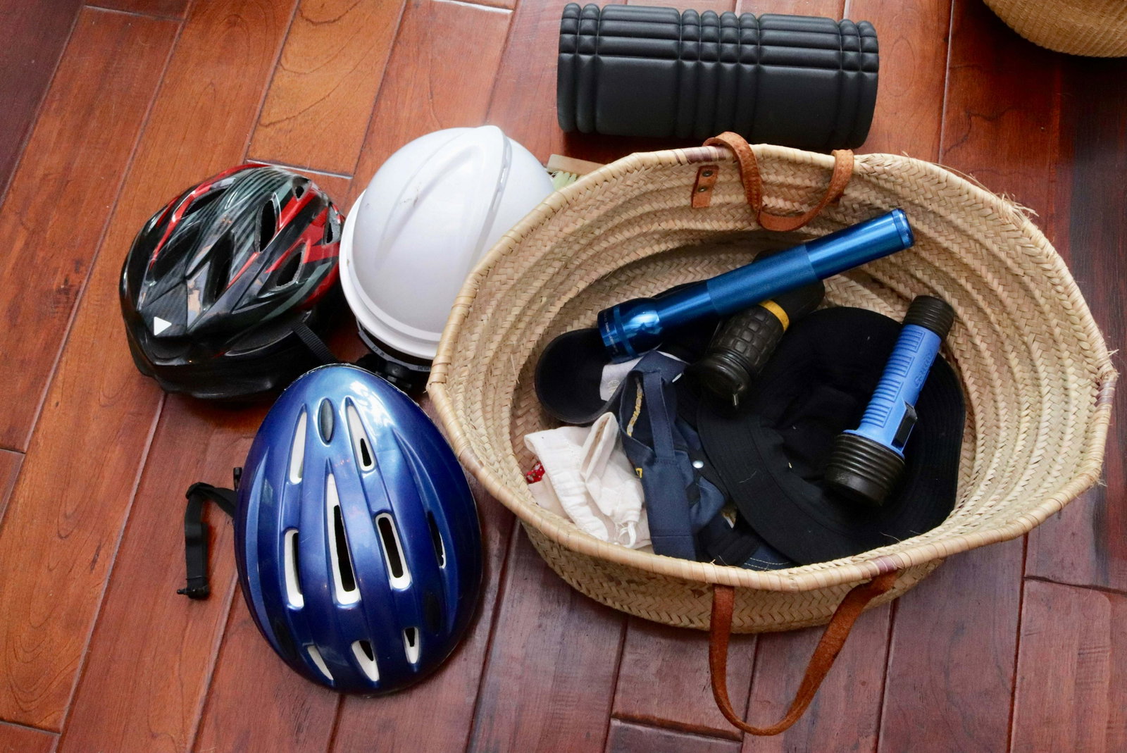 HANDLED BASKET OF HOUSEHOLD ITEMS: INCLUDING: BICYCLE HELMETS, FLASHLIGHTS, FOAM ROLLER, HATS AND MORE