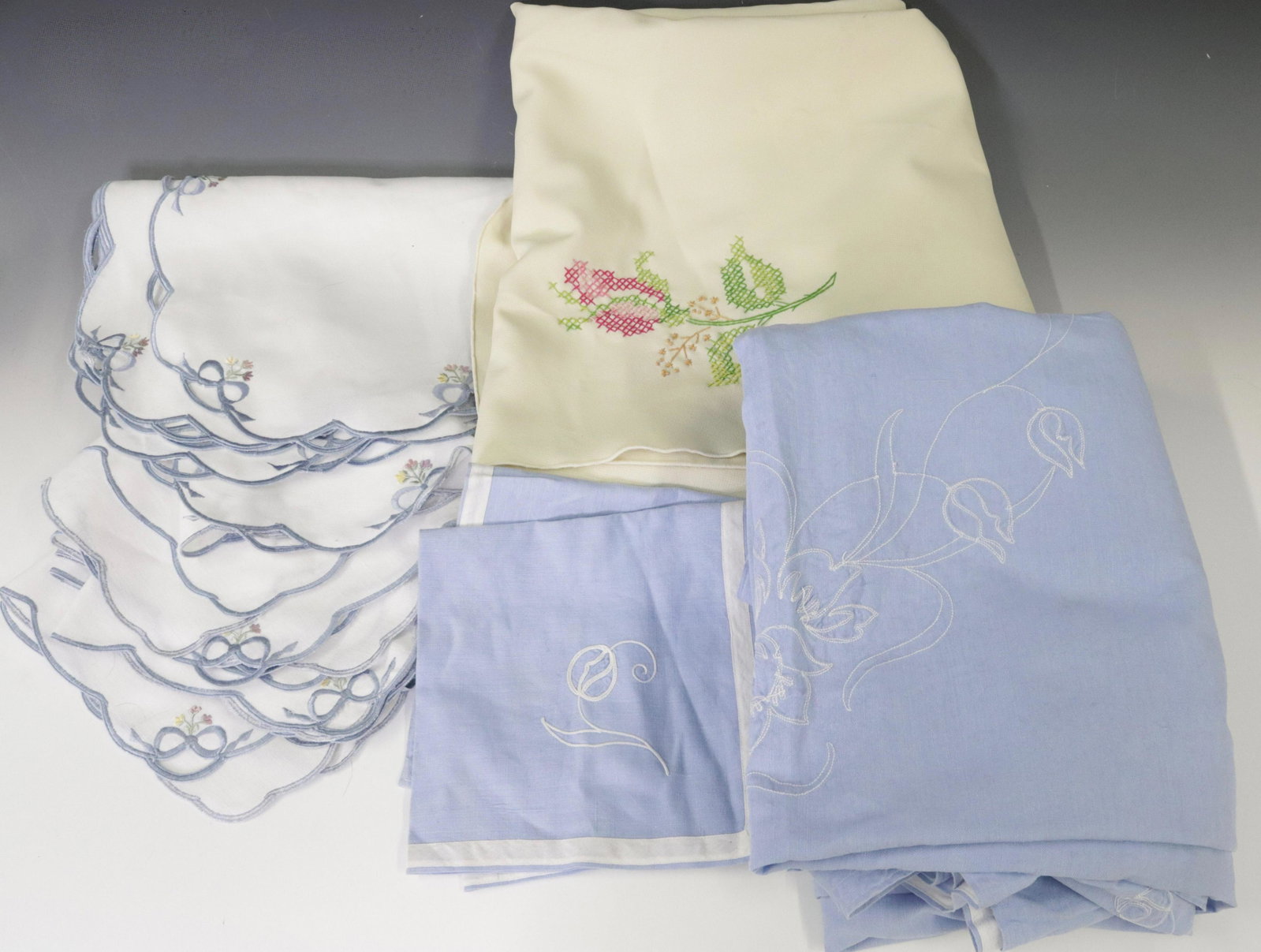 GROUP LOT OF VINTAGE DRYGOODS: INCLUDES: OVAL CROSS STITCHED TABLECLOTH, BLUE EMBROIDERY TABLECLOTH WITH TWO NAPKINS, SIX MATCHING PLACEMATS WITH NAPKINS Dimensions OVAL 88" L, BLUE RECTANGULAR 98" X 66",