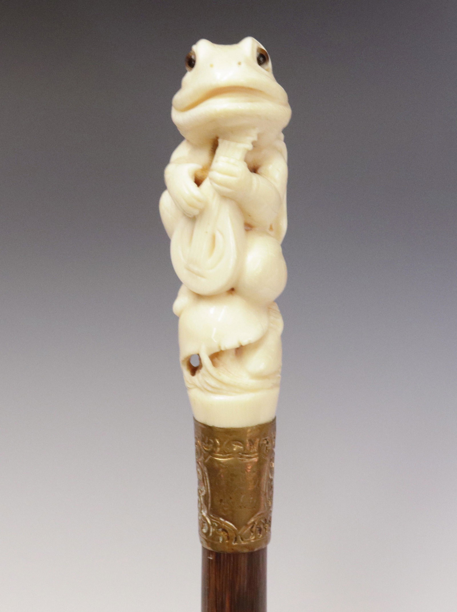 "MR. TOAD" CARVED BONE CANE: MR. TOAD IS THE FAMOUS CHARACTER FROM KENNETH GRAHAME'S - FAMOUS BOOK "WIND OF WILLOWS" - MR. TOAD IS WEARING BREECHES, WEARING A CAPE WITH LONG TAILS, AND BUCKLED SHOES - PLAYING MANDOLIN - STEPPED P