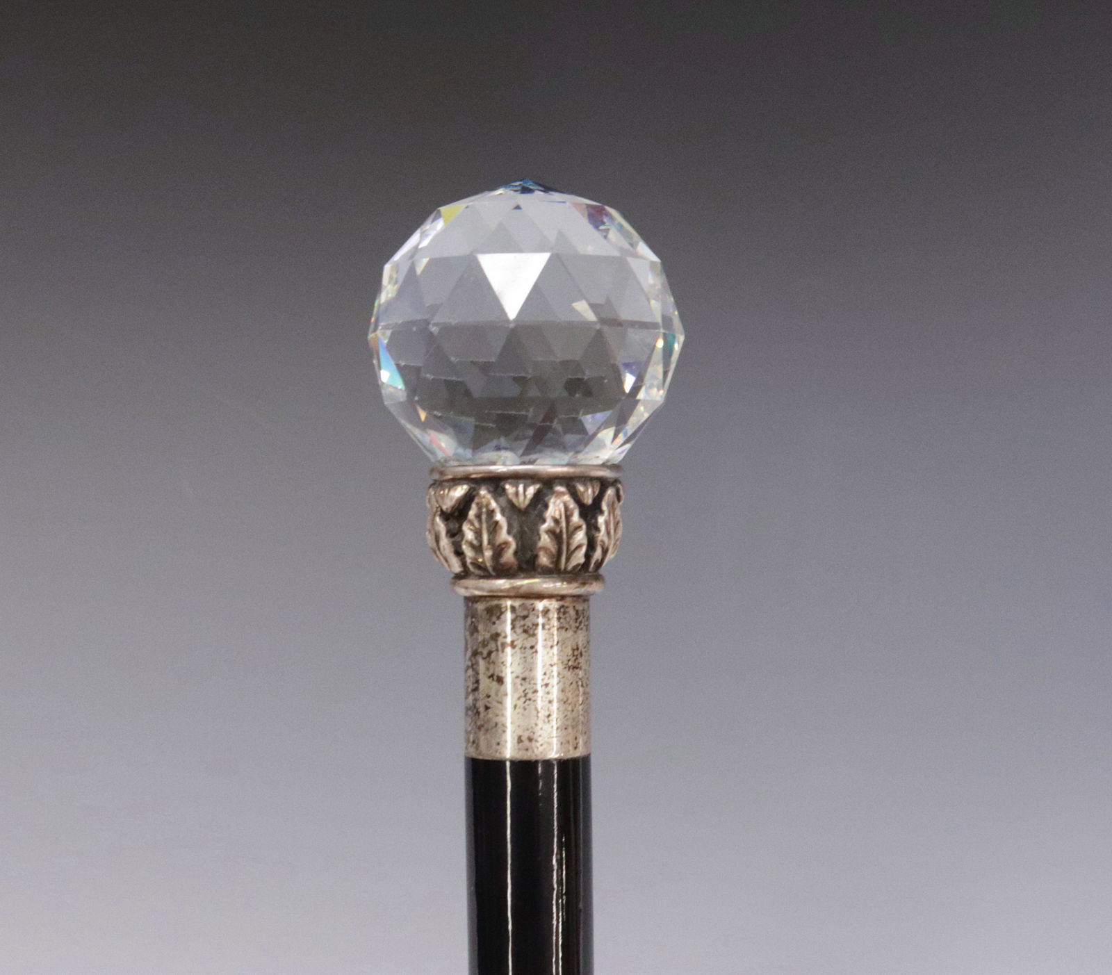 FACETED CRYSTAL CANE: CRYSTAL BALL CUT IN DIAMOND FACETS AND SITS ON SILVER BASE DECORATED WITH A RING OF ACANTHUS LEAVES - LOWER RING MARKED .925 WITH CONTINENTAL HALLMARKS - CIRCA 1900 - EBONY SHAFT WITH BRASS FERRULE 36