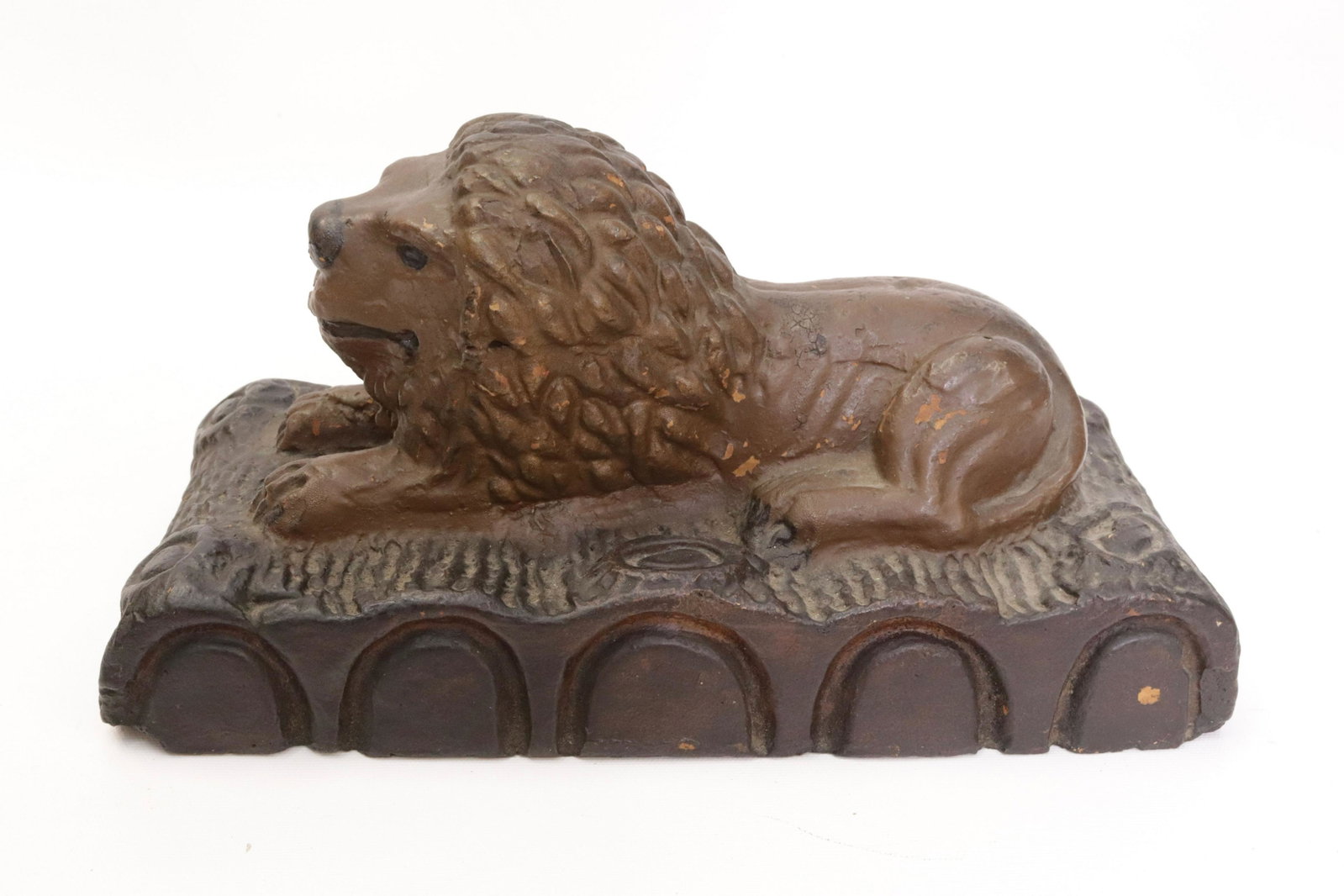 FOLK ART LION DOORSTOP: MOLDED POTTERY. PAINTED SURFACE. LION RECLINING ON LOGS. 6 1/2" X 12 1/2" X 6"