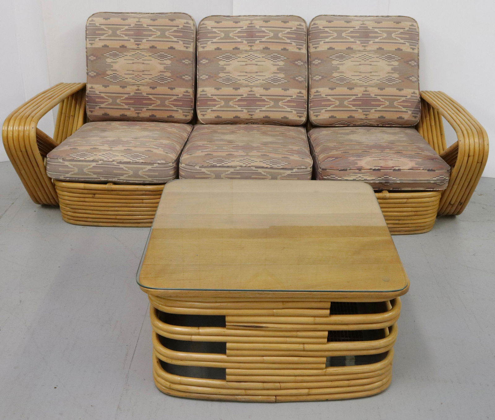 PAUL FRANKL RATTAN COUCH AND COFFEE TABLE: INCLUDES: THREE-PIECE SECTIONAL SOFA AND COFFEE TABLE. UPHOLSTERED CUSHIONS AND GLASS TOP ON TABLE SURFACE SOFA 30" X 79" X 32"