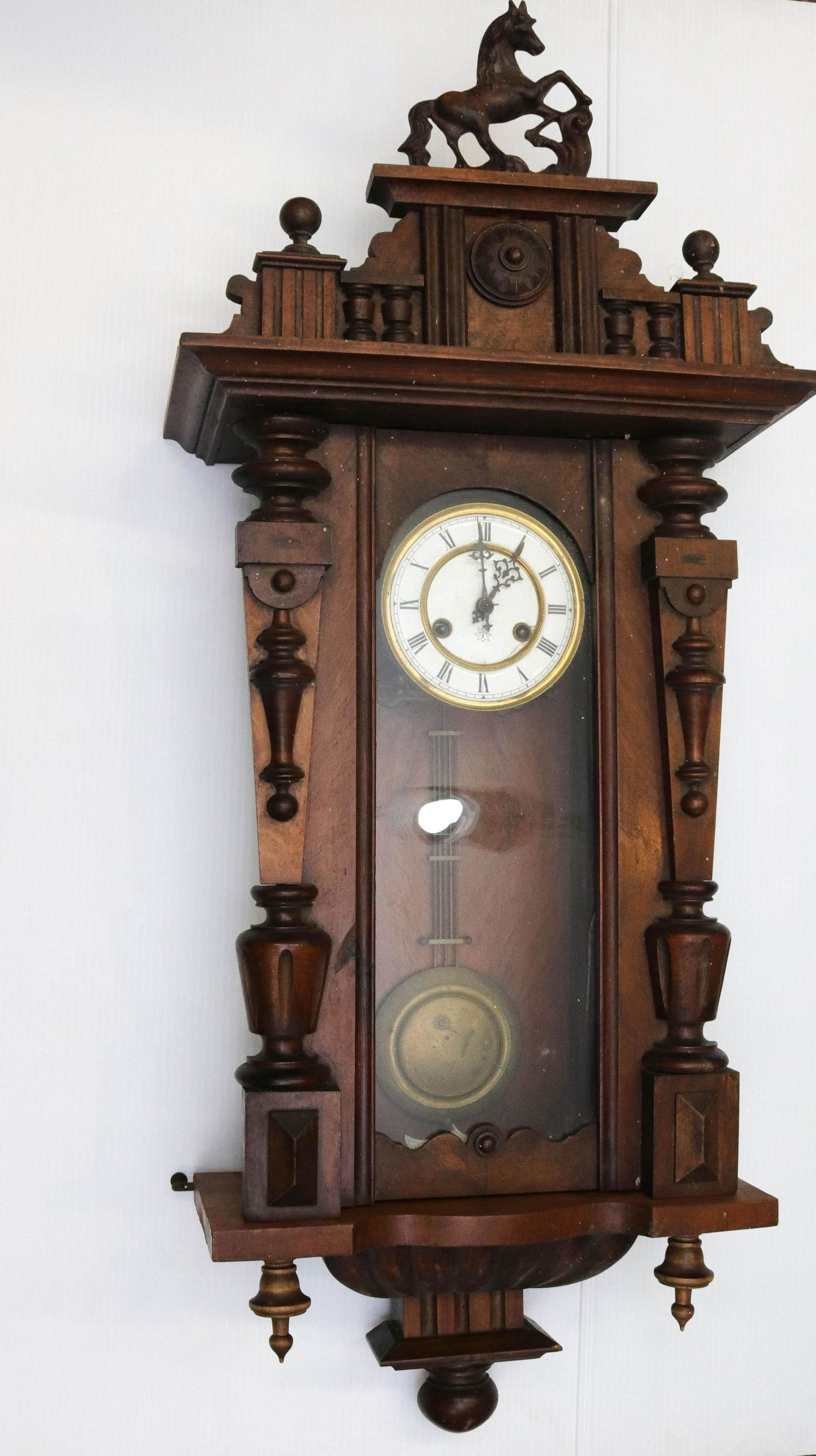 JERGEN UNGHANS WALL CLOCK: BRASS PENDULUM WITH PORCELAIN DIAL. MAHOGANY CASE WITH HORSE TOPPER Dimensions 40" X 17"