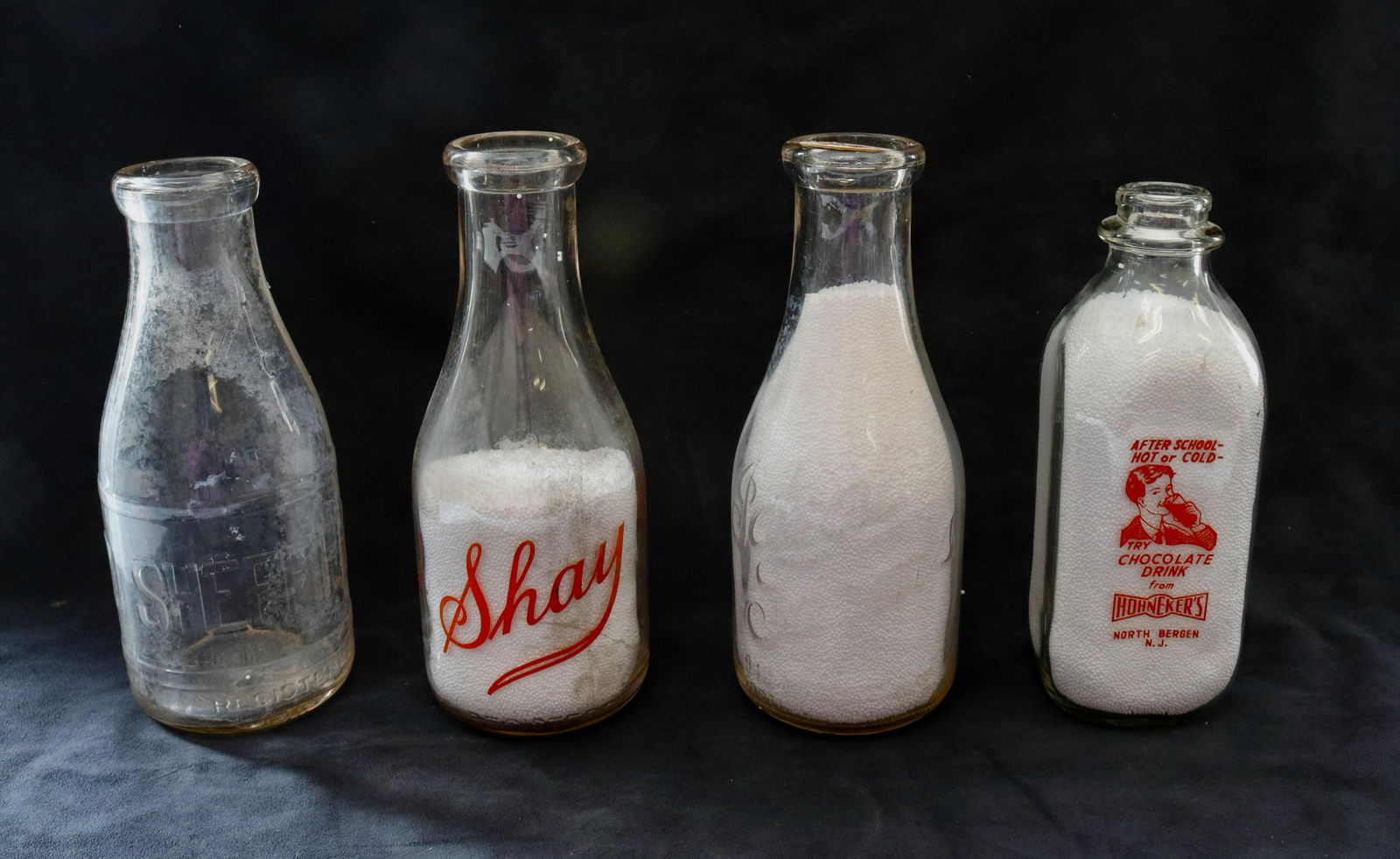 Vintage milk bottle lot: Description: (4) including - sheffield, riverside dairy (matamoras, pa), ideal farms, and hohneckers (north bergen, nj) Condtion: Normal wear Size: 9" TO 9 1/2" H Consignor: JS Terms: This is an On