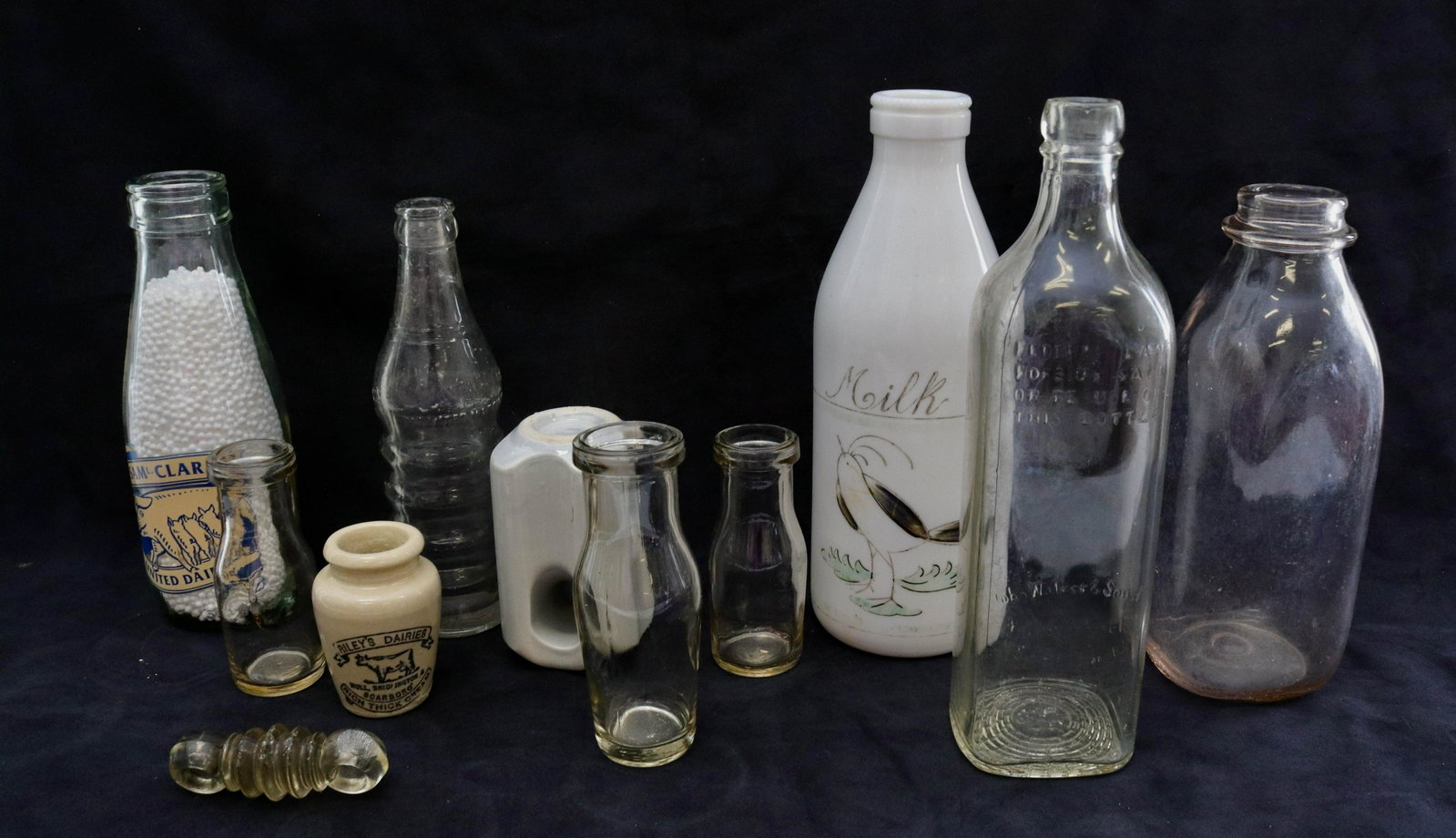 Group lot of vintage bottles: Description: (6) milk bottles, liquor bottle, and sweeney soda bottle - riley's dairy crock and (2) insulators Condtion: Wear consistent with age and use Size: 2 3/4" TO 10" Consignor: JS Terms: T
