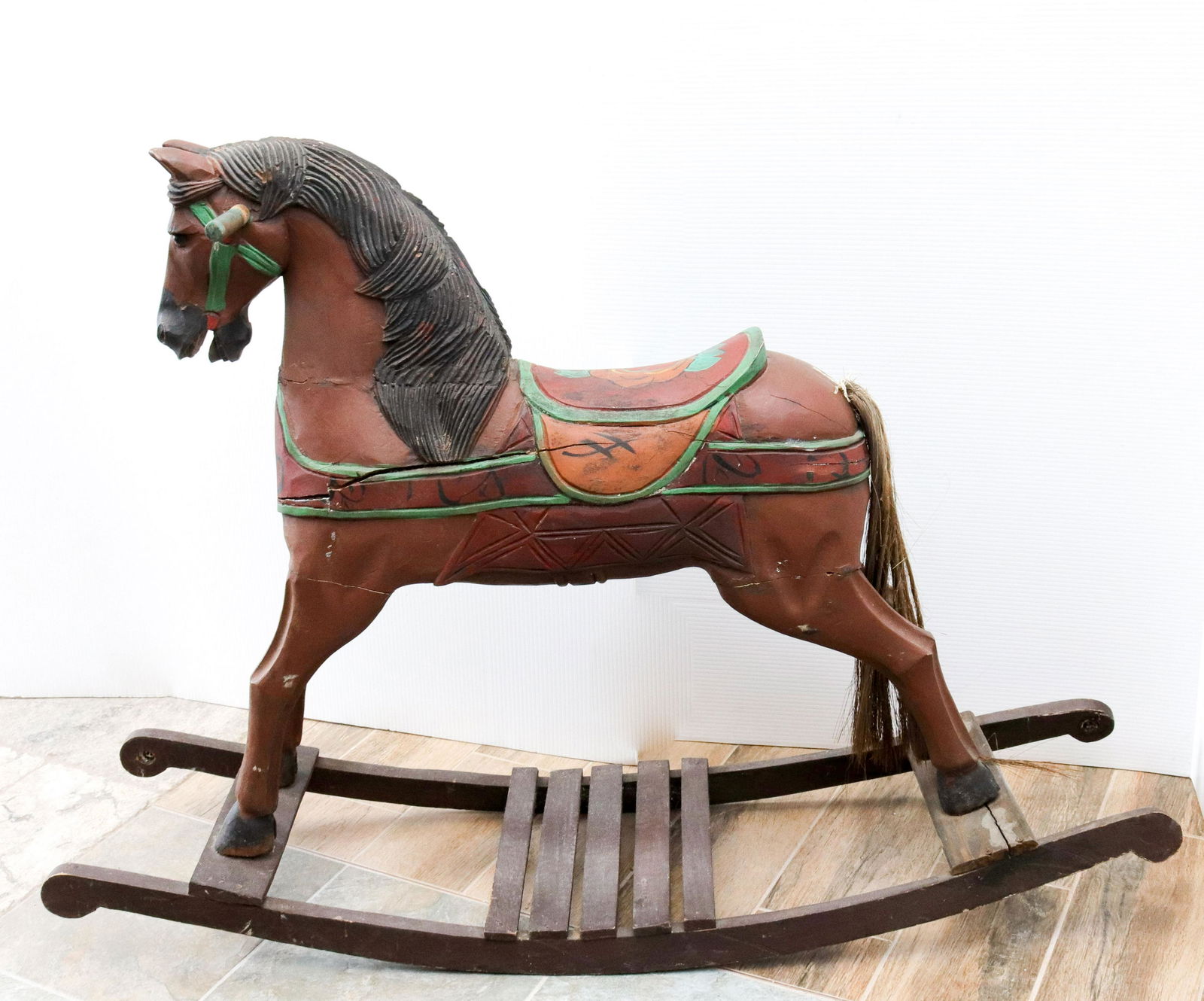 Carved and painted wooden rocking horse: Description: Decorative childs rocking horse with broom hair tail Condtion: Loss to painted surface - detached handle Size: 32" X 45" Consignor: JS Terms: This is an On-Site Online Only Auction. P