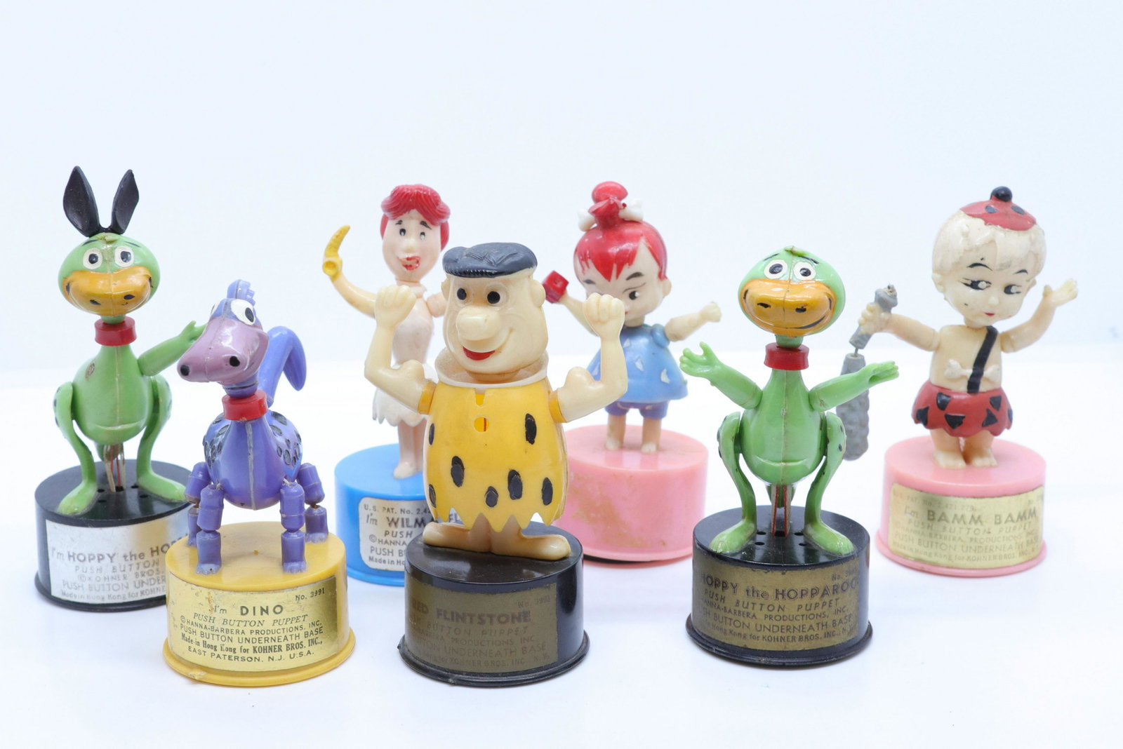 Flintstones push button puppet group: Description: (7) kohner bros. new york - hanna-barbera productions - plastic figures Condtion: One hoppy is missing ear and other missing arm - wear consistent with age and use Size: 3 3/4" H Consigno