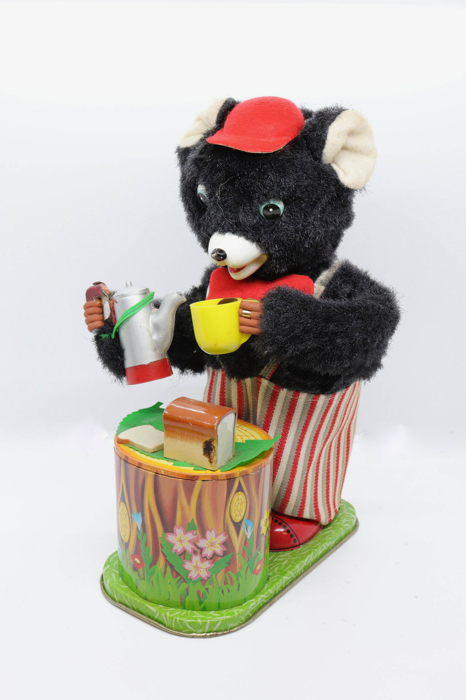 Battery operated tin lithograph bear: Description: Bear with teapot eating at stump - tin litho and plush - made in japan Condtion: Wear consistent with age and use Size: 10" H Consignor: JS Terms: This is an On-Site Online Only Auctio