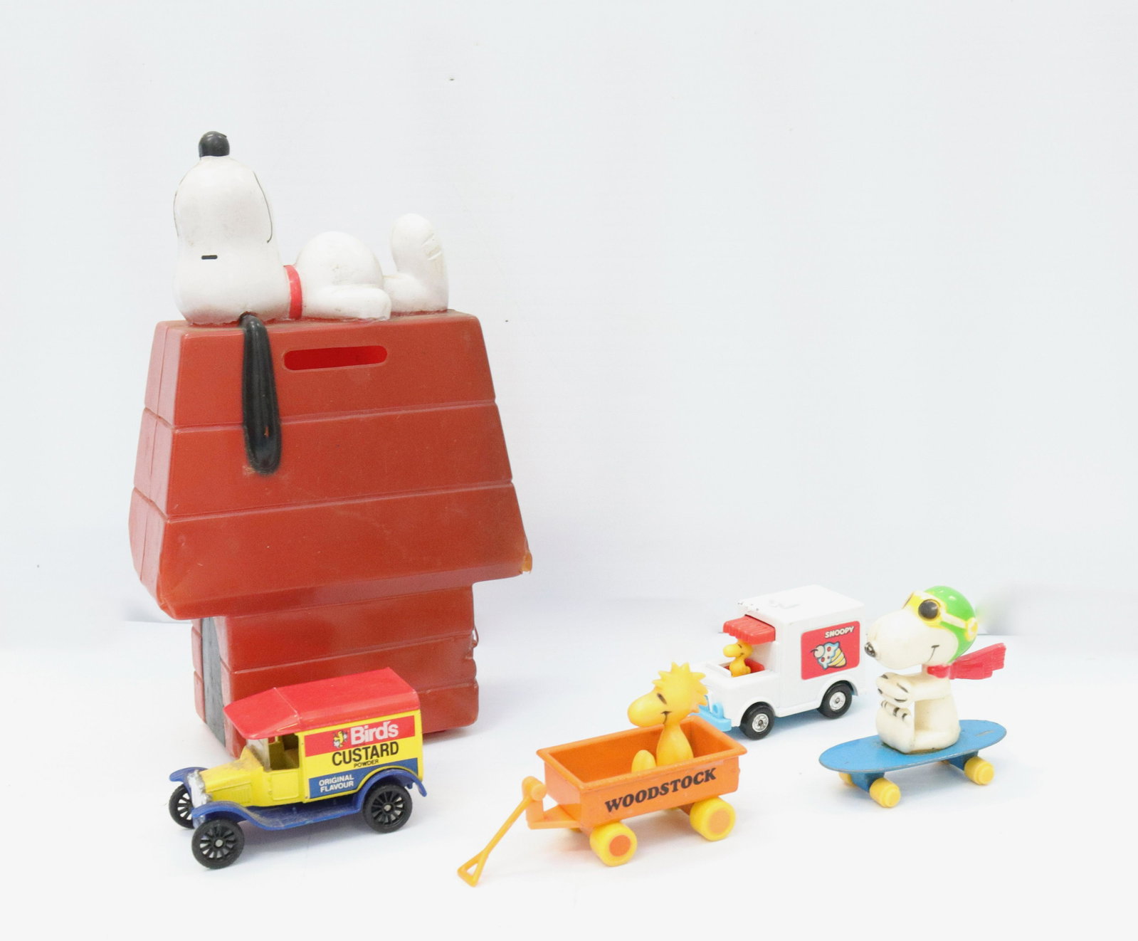 Group lot of snoopy items: Description: Including - plastic bank, snoopy on skateboard, woodstock in wagon, and woodstock driving icecream truck Condtion: Normal wear - bank missing trap on bottom Size: BANK 7" X 4 1/2" Consign