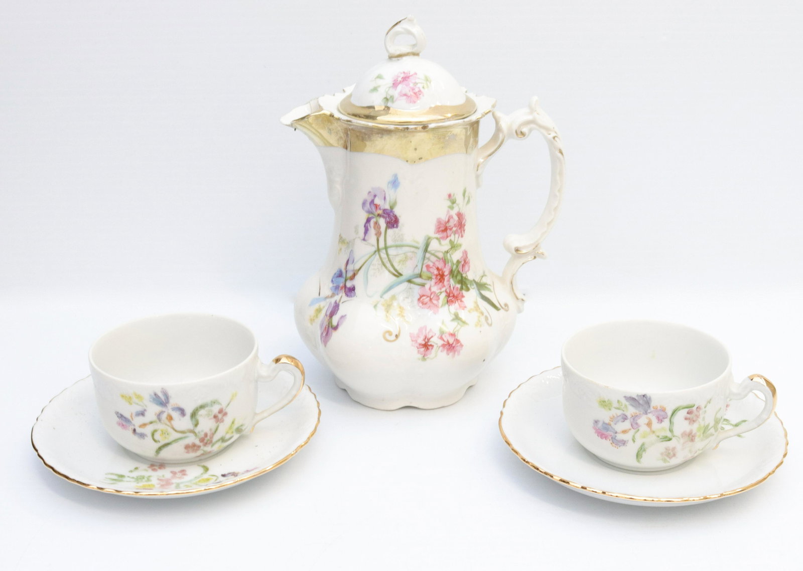 German porcelain lot: Description: Porcelain coffee pot, (2) cups, and (3) saucers - iris decorations Condtion: Repair to spout and lid Size: POT 9" X 6 1/2" Consignor: JS Terms: This is an On-Site Online Only Auction.