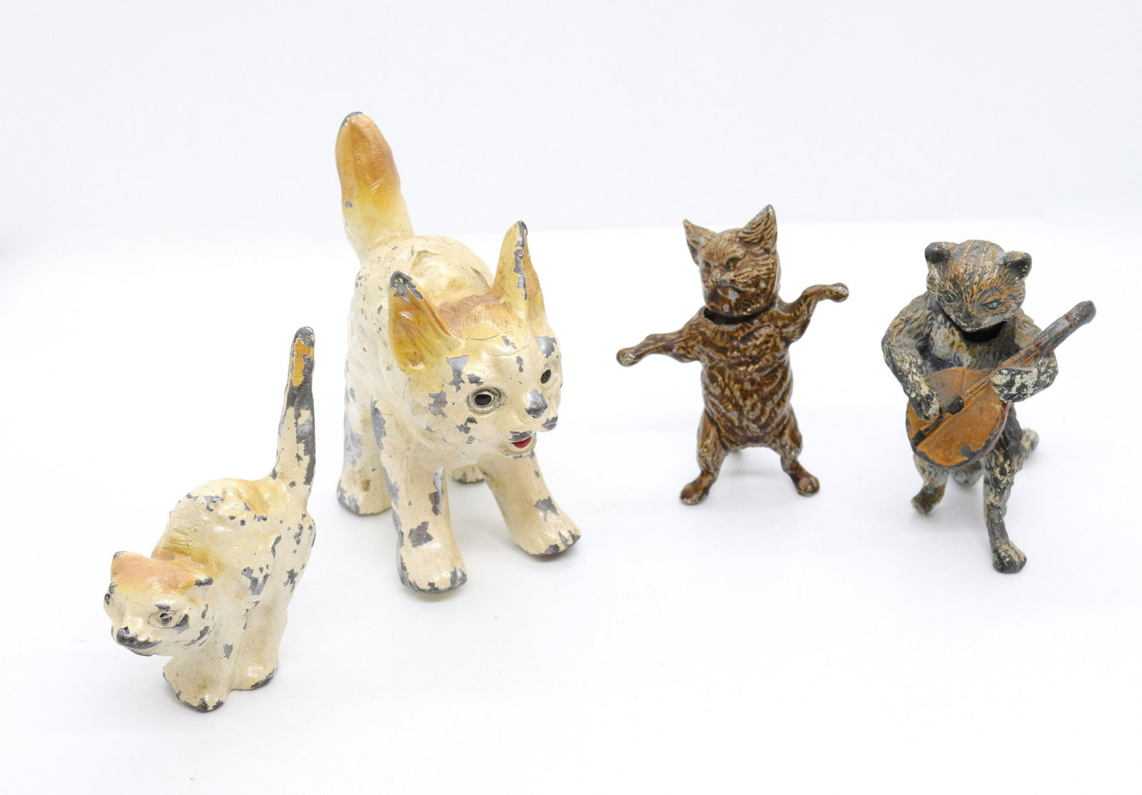 Miniature cat figurine lot: Description: (4) including - nodder with spring, (2) cast metal cream cats, and cat nodder with banjo (loss to neck) Condtion: Wear to neck of one - others have minor wear and loss to painted surface