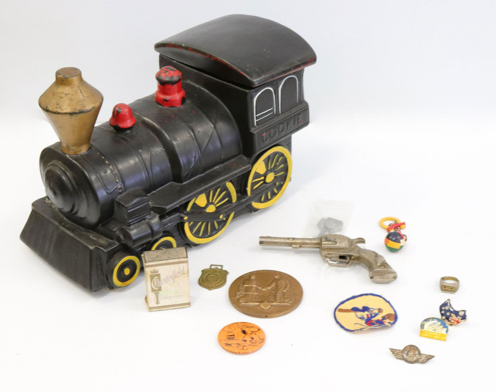 Mccoy locomotive cookie jar and smalls: Description: Including: smoky cap gun, chesterfield ashtray, mickey mouse patch, bronze medal and more Condtion: Cookie jar has some wear to paint Size: JAR IS 12" L Consignor: JS Terms: This is an