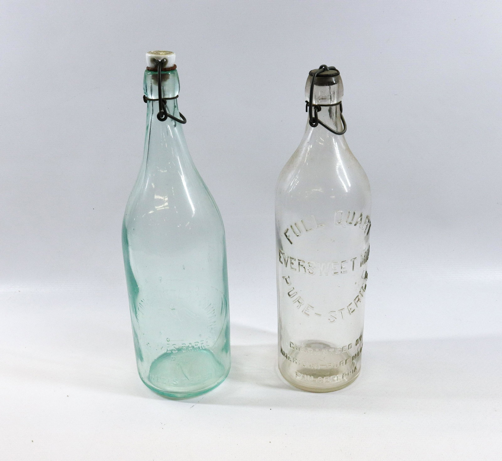 PAIR OF VINTAGE EMBOSSED BOTTLES: KEYSTONE BOTTLING COMPANY (AQUA WITH PORCELAIN STOPPER) AND CLEAR EVERSWEET MILK WITH METAL STOPPER Size 11 1/2" TO 12 1/4" H