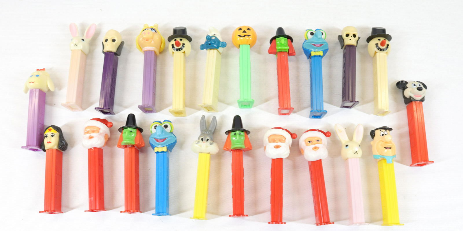 GROUP LOT OF VINTAGE PEZ DISPENSERS: (22) CONTAINERS WITH FEET INCLUDING: SANTA CLAUS, EASTER, WITCH, SMURF, SKELETON, FRED FLINTSTONE AND MORE