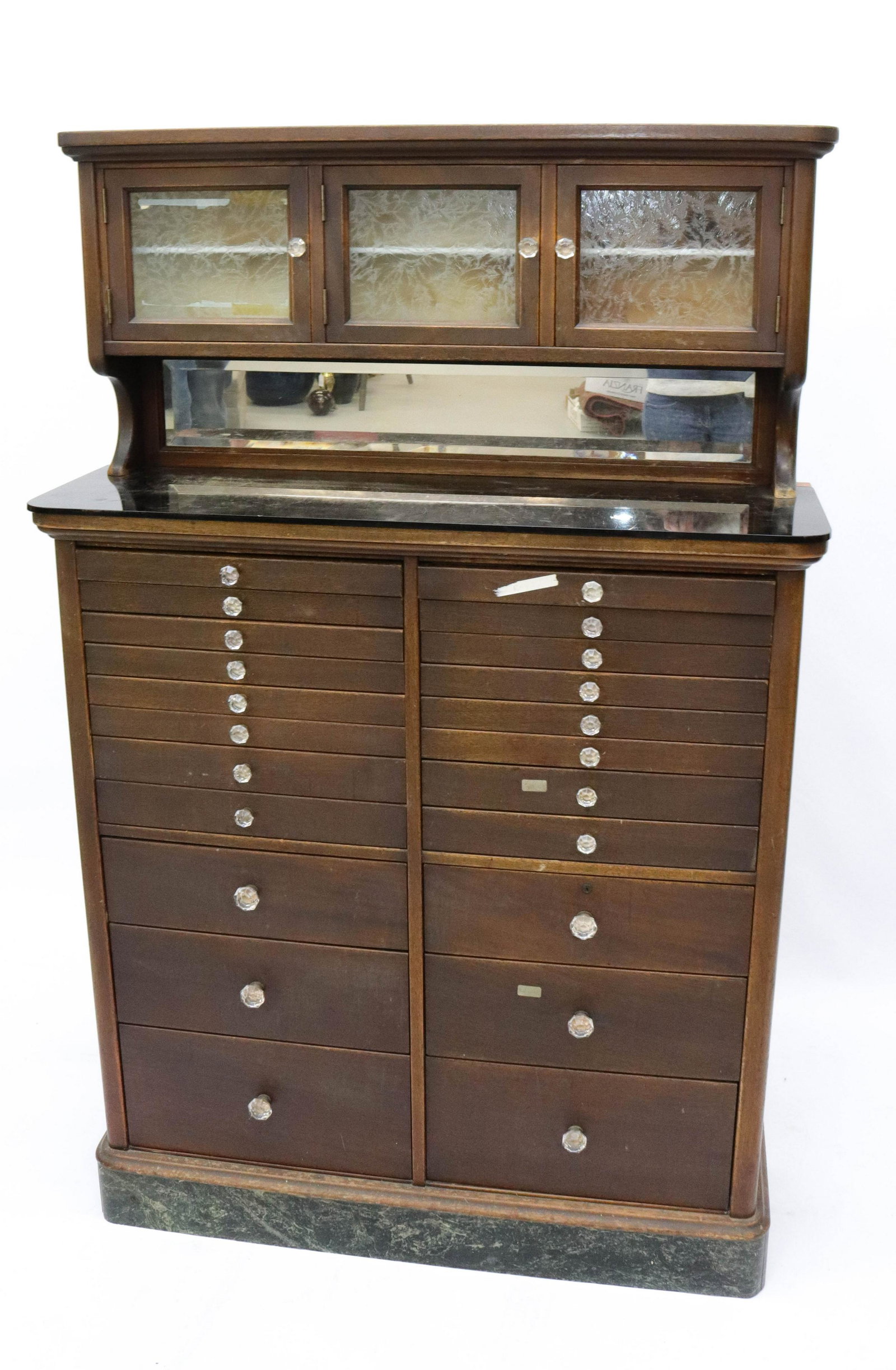 VINTAGE DENTAL CABINET: ONE PIECE DENTAL CABINET - THREE DOORS WITH ETCHED GLASS INSERTS AND GLASS KNOBS OVER 22 DRAWERS - BLACK GLASS SHELF OR TOP AND BEVELED MIRROR BACK ON MARBLE BASE SIZE: 63" X 40" X 13"