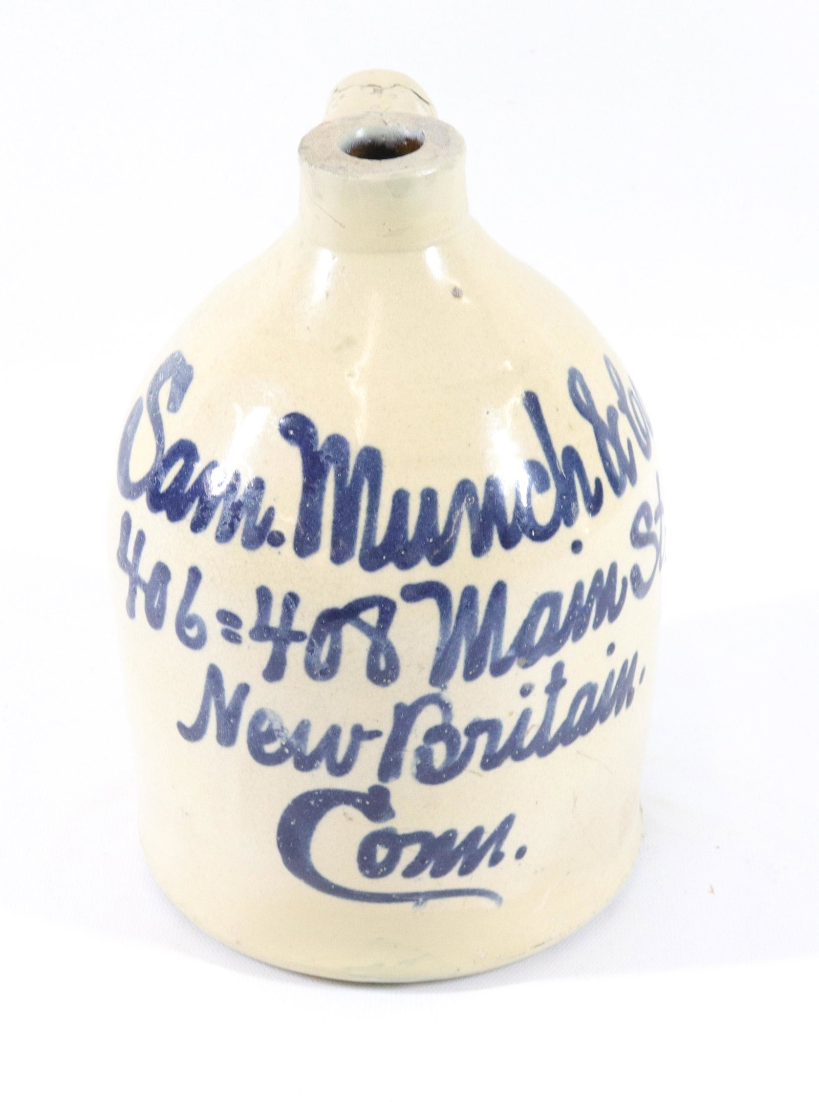BLUE DECORATED STONEWARE SCRIPT JUG: SAM MUNCH & CO. - 406-408 MAIN ST. NEW BRITAIN, CONN SIZE: 9" X 5 3/4"