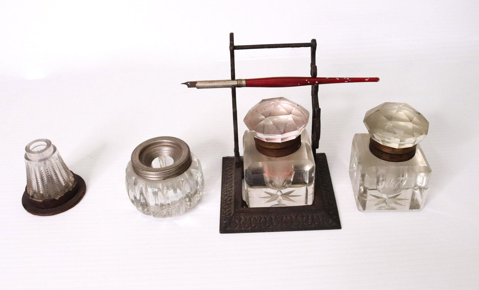 GROUP LOT OF INKWELLS: (4) GLASS INKWELLS - ONE WITH METAL TRIM MARKED "THE CLIMAX" - LARGEST IS ON CAST IRON BASE WITH PEN HOLDER