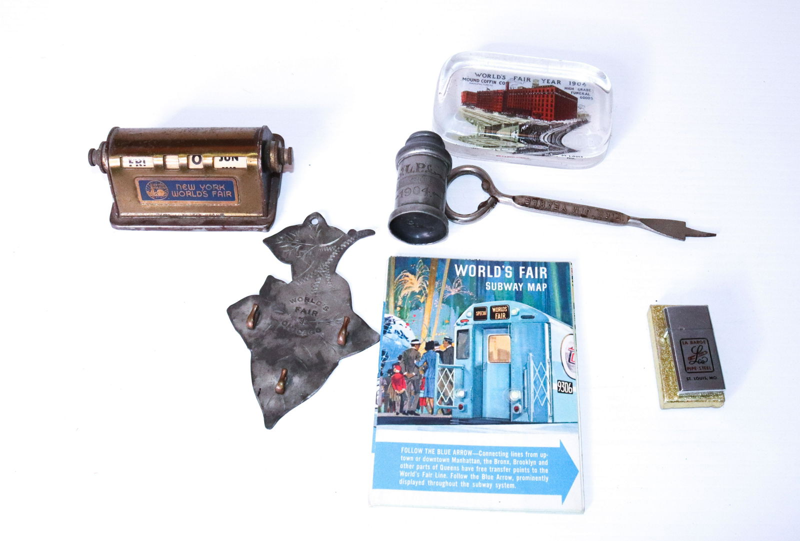 GROUP LOT OF WORLD'S FAIR ADVERTISING ITEMS: INCLUDING - 1904 WORLD'S FAIR MOUND COFFIN CO, NEW YORKS WORLDS FAIR DESK CALENDAR, 1904 WORLD FAIR SHAKER, LA BARGE PIPE STEEL LIGHTER, AND YEAKLE FOR MAYOR OPENER