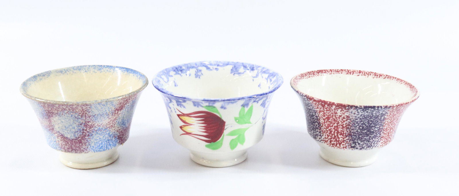 (3) SPATTERWARE DECORATED CUPS: INCLUDING: PURPLE WITH BLUE DOTS, PURPLE/RED STRIPED AND BLUE SPONGE WITH TULIP Dimensions 2 1/2" H PLEASE READ BEFORE BIDDING – PICKUP FOR THIS AUCTION WILL NOT BE UNTIL THE WEEK OF OCTOBER 25T
