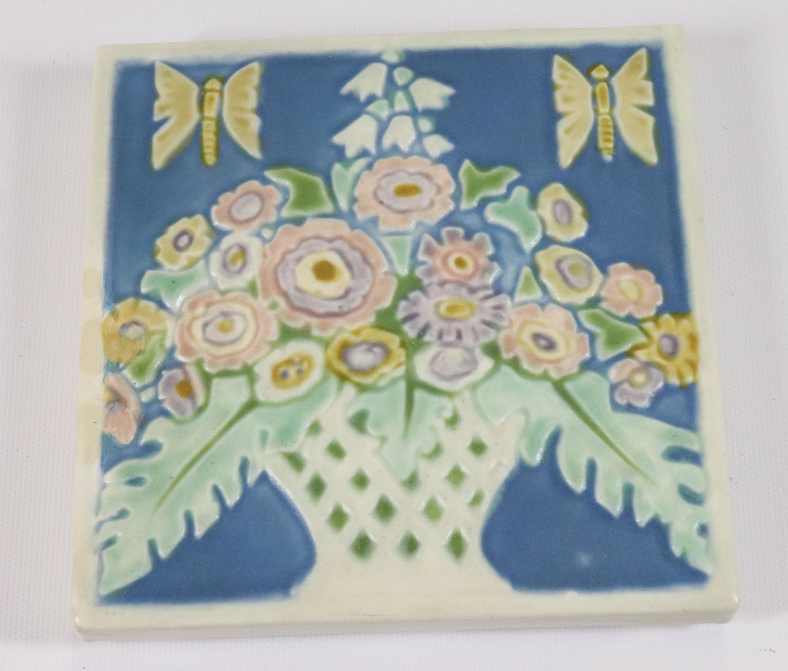ROOKWOOD POTTERY TRIVET: FLOWER BASKET, CIRCA 1925 SIZE: 5 3/4" X 5 3/4" X 3/4" PLEASE READ BEFORE BIDDING – PICKUP FOR THIS AUCTION WILL NOT BE UNTIL THE WEEK OF OCTOBER 25TH. PICK-UP WILL BE FROM 9:00AM TILL 4:00PM – YO