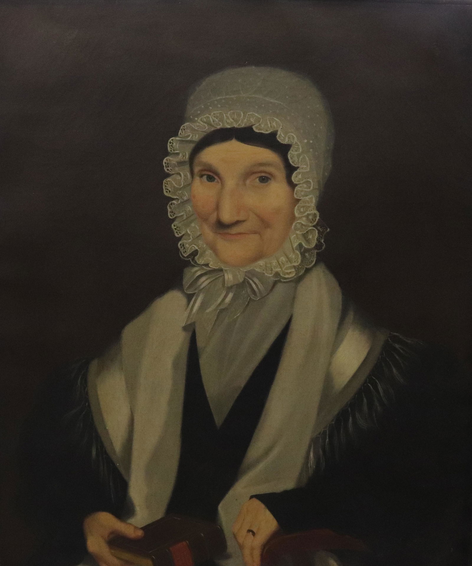 EARLY 19TH C. AMERICAN PORTRAIT OF WOMAN: ATTRIBUTED TO AMMI PHILLIPS (1788-1865). OIL ON CANVAS. ELDER WOMAN SEATED IN ARMCHAIR WITH HAND ON PSALMS AND HYMNS BOOK. DATED 1834 WITH ILLEGIBLE SITTER'S NAME ON VERSO SIZE: SIGHT VIEW 30" X 25 1/