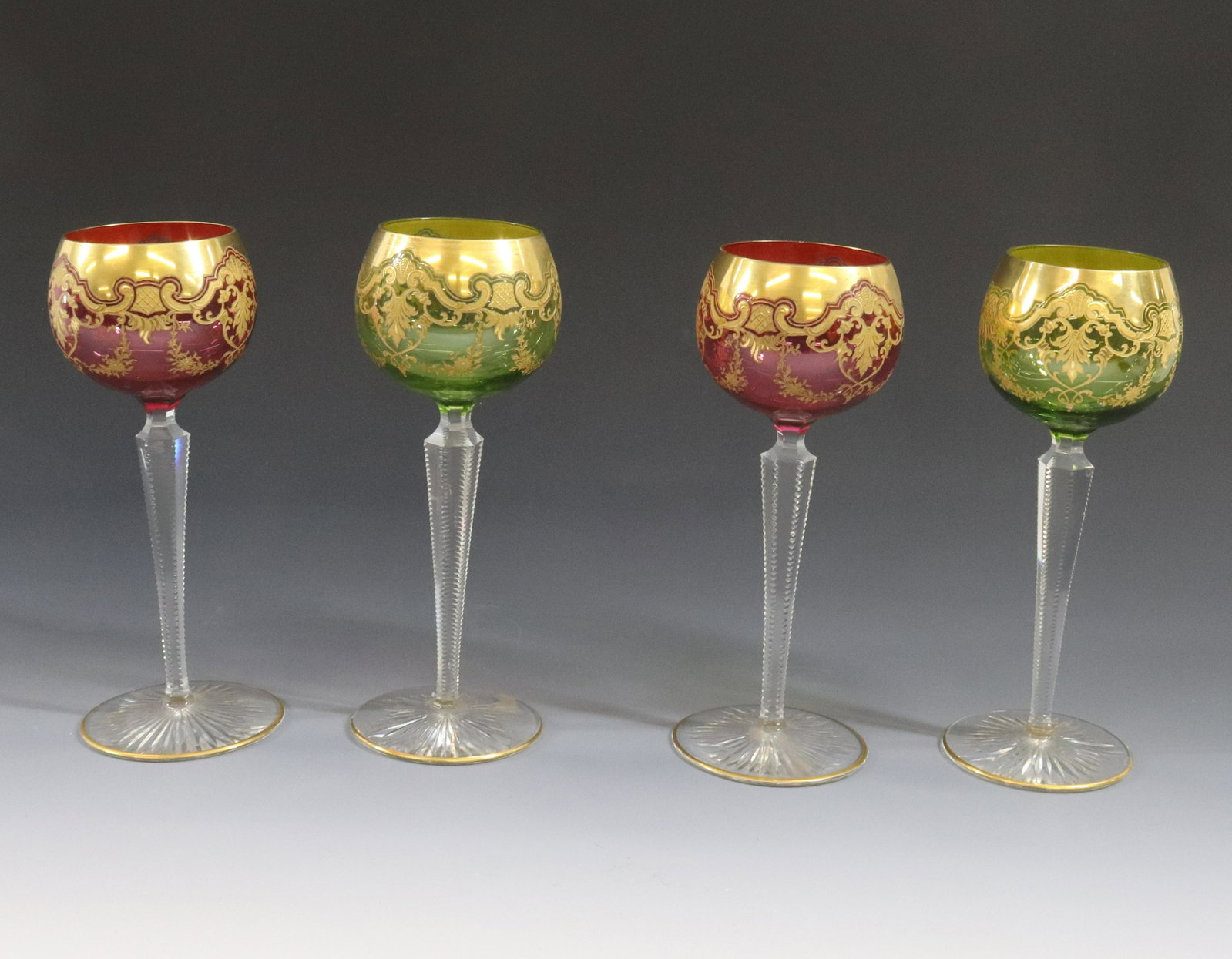 MOSER GLASS STYLE GOBLETS: ORNATE GOLD DECORATION, (2) IN CRANBERRY AND (2) IN GREEN DIMENSIONS: 7 1/2" TERMS: Hartzell's Auction Gallery will handle most of the shipping in-house. WE do reserve the right to not ship some large