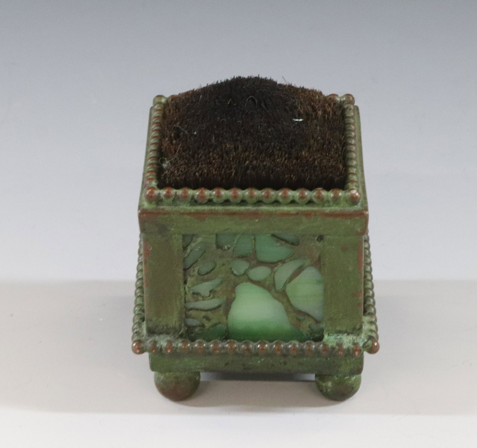 BRONZE AND SLAG GLASS DIP PEN CLEANER: GREEN PATINA WITH GREEN SLAG GLASS NATURAL BRISTLE SIGNED ON BASE POSSIBLY TIFFANY STUDIOS THE WORD "STUDIO" IS READABLE. DIMENSIONS: 2" DIA TERMS: Hartzell's Auction Gallery will handle most of the s