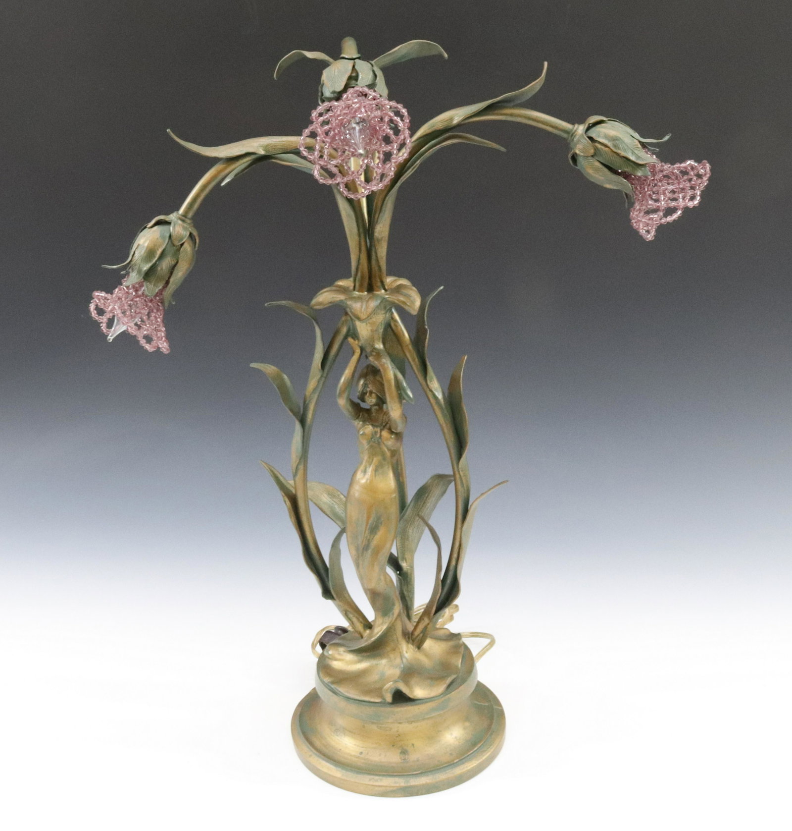 FRENCH ART NOUVEAU LILY LAMP: THREE LIGHT WITH ART NOUVEAU MAIDEN HOLDING LILY BLOOM APPLIED LEAVES AND BEADED GLASS BULB COVERS PAINTED IN GREEN AND GOLD DIMENSIONS: 21"H X 15" TERMS: Hartzell's Auction Gallery will handle most o