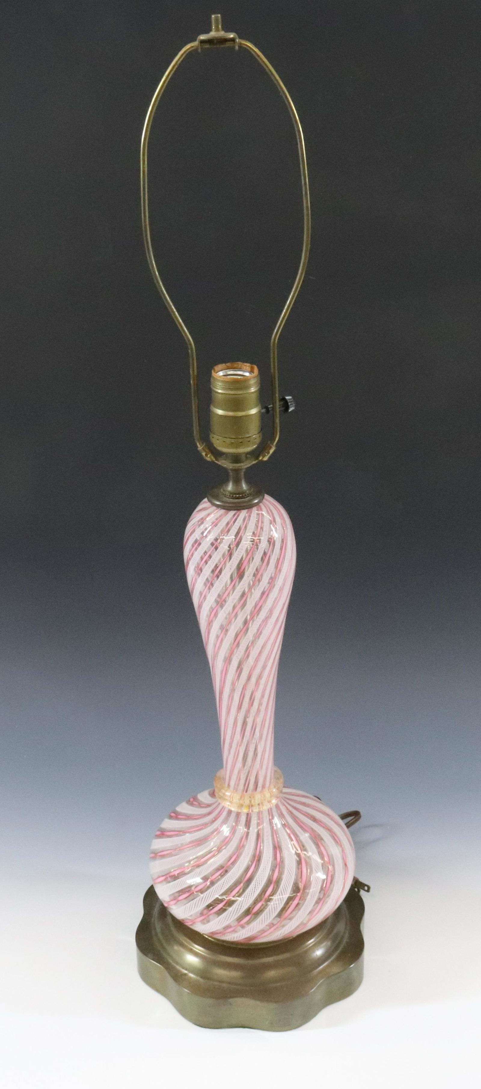 VENETIAN LATTICINO LAMP: WHITE AND PINK WITH GOLD FLECKS MOUNTED ON BRASS BASE DIMENSIONS: 28"H TOP OF HARP X 7 1/2" DIA TERMS: Hartzell's Auction Gallery will handle most of the shipping in-house. WE do reserve the right to 