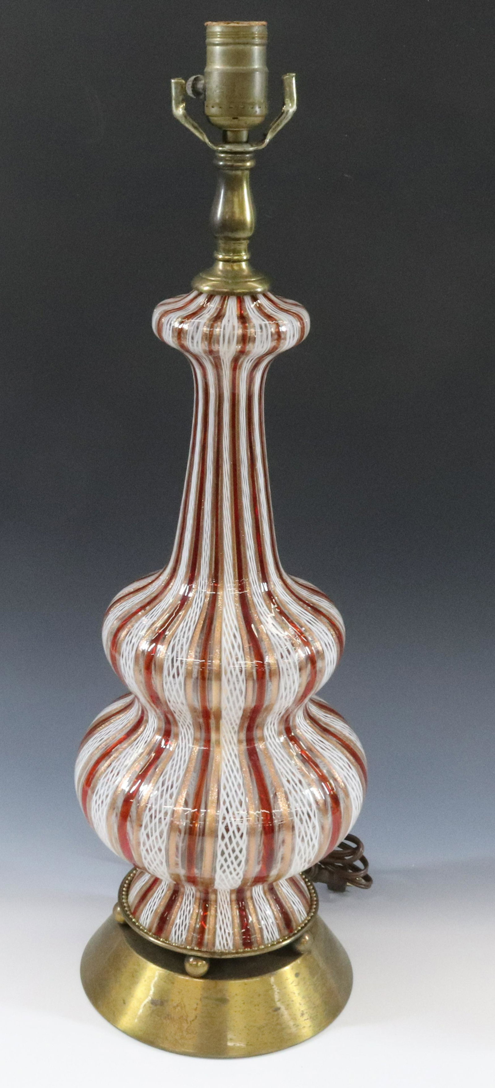 VENETIAN LATTICINO LAMP: RED WHITE AND GOLD MOUNTED ON BRASS BASE DIMENSIONS: 23 1/2" X 7" DIA TERMS: Hartzell's Auction Gallery will handle most of the shipping in-house. WE do reserve the right to not ship some large items,