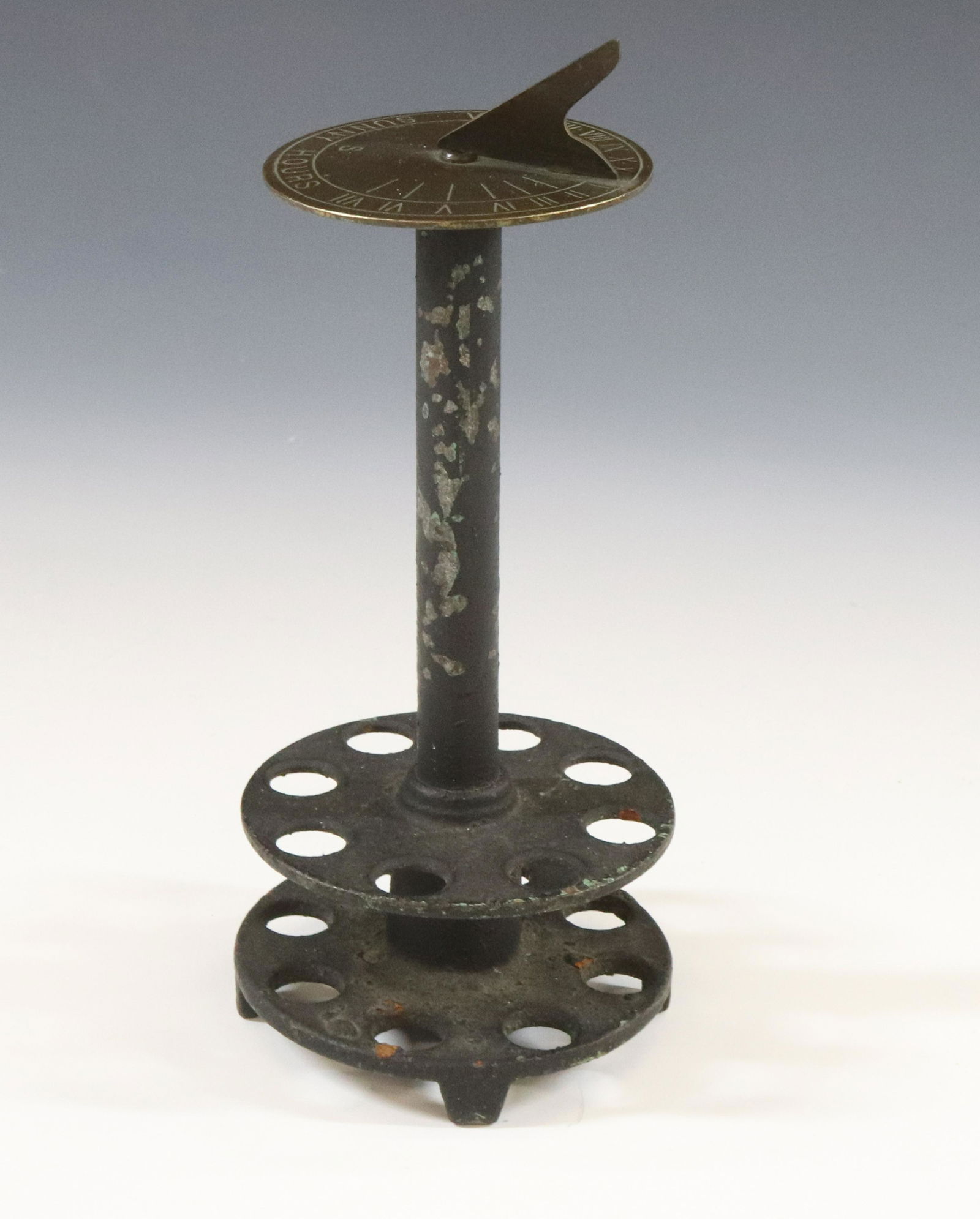 HOLZWORTH FLOWER FROG: WITH BRONZE SUNDIAL "HAPPY HOURS" CAST IRON BASE UNUSUAL ITEM DIMENSIONS: 7"H X 2 3/4" TERMS: Hartzell's Auction Gallery will handle most of the shipping in-house. WE do reserve the right to not ship