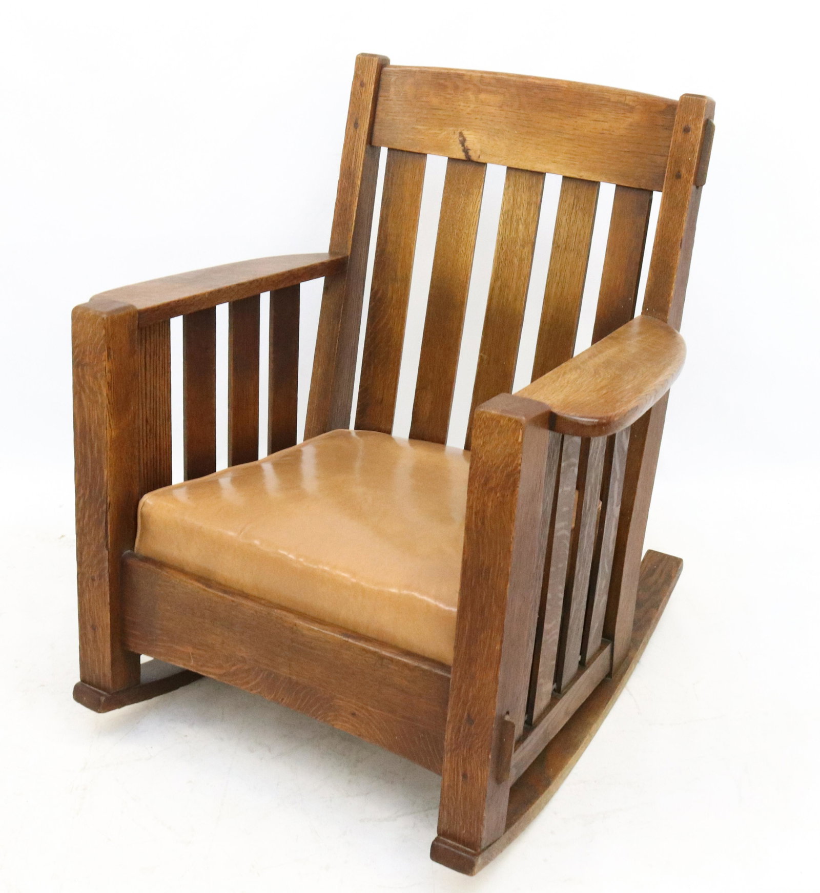 ARTS & CRAFTS OAK ROCKING CHAIR: MORTISE AND PIN CONSTRUCTION WITH UPHOLSTERED LEATHER SEAT DIMENSIONS: 33" X 31" X 24" TERMS: Hartzell's Auction Gallery will handle most of the shipping in-house. WE do reserve the right to not ship 