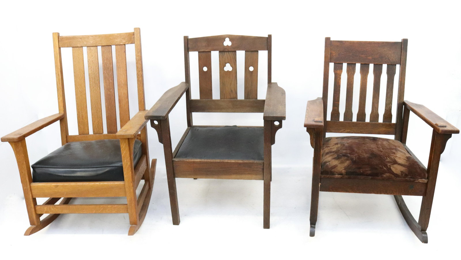 GROUP LOT OF ARTS & CRAFTS FURNITURE: TWO ROCKING CHAIRS WITH ONE ARMCHAIR. UPHOLSTERED SEATS. ROCKERS HAVE MORTISED CONSTRUCTION. ARMCHAIR HAS DECORATIVE CUT-OUTS. DIMENSIONS: LARGEST 37 1/2" X 26 1/4" X 22" TERMS: Hartzell's Auction Gal
