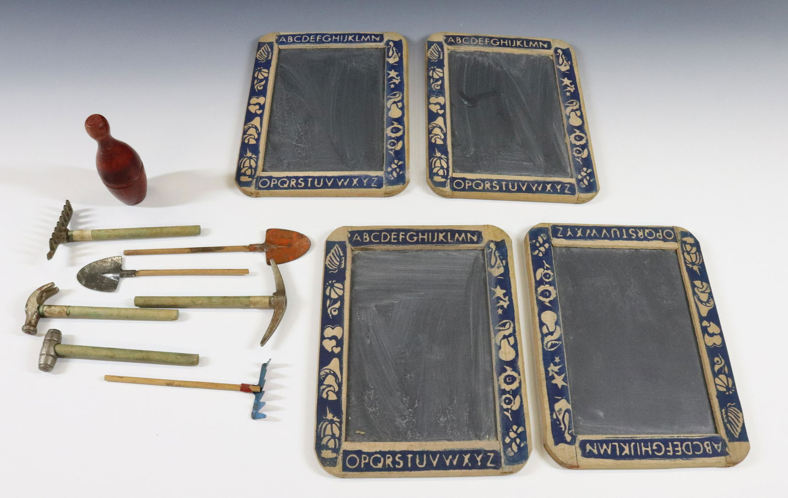 SCHOOL SLATEBOARDS, MINIATURE TOOLS AND BOWLING PIN: (4) SLATE BOARDS WITH ALPHABET AROUND EDGE, (7) MINIATURE GARDEN TOOLS AND WOODEN BOWLING PIN IN RED WASH WITH SMALLER PINS INSIDE Size: SLATES 7 3/4" X 5 3/4" Terms: Hartzell's Auction Gallery will h