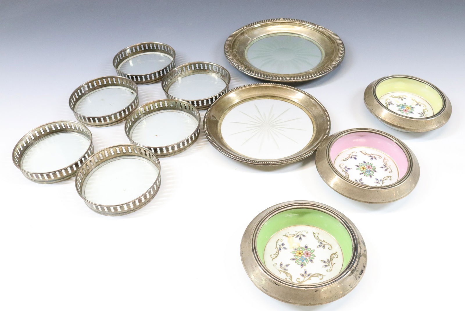 STERLING SILVER COASTER GROUPING: (11) THREE MATCHING WITH PORCELAIN INSERTS, SIX MATCHING, AND TWO WINE BOTTLE COASTERS DIMENSIONS: 3" TO 6 1/4 DIA TERMS: Hartzell's Auction Gallery will handle most of the shipping in-house. WE do re