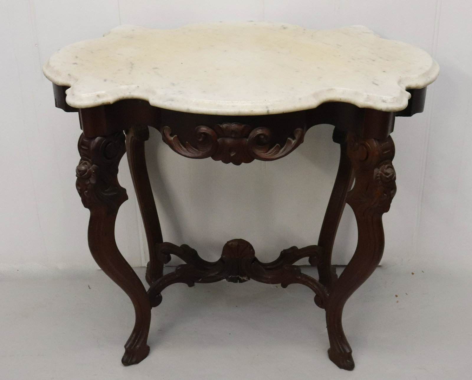 VICTORIAN MARBLE TOP TABLE: CARVED WALNUT TABLE WITH SCALLOPED MARBLE TOP DIMENSIONS: 28" X 33" X 21 1/2" TERMS: Hartzell's Auction Gallery will handle most of the shipping in-house. WE do reserve the right to not ship some larg