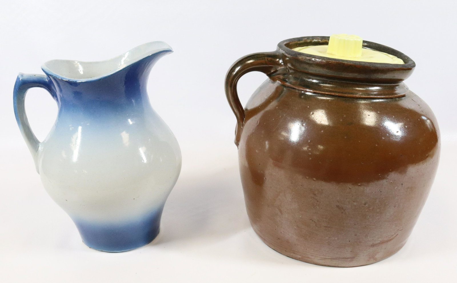 STONEWARE MILK PITCHER AND BEAN POT: BLUE/WHITE SALT GLAZED PITCHER AND BROWN GLAZED BEAN POT (MISSING CORRECT LID). PITCHER MEASURES 10" H.