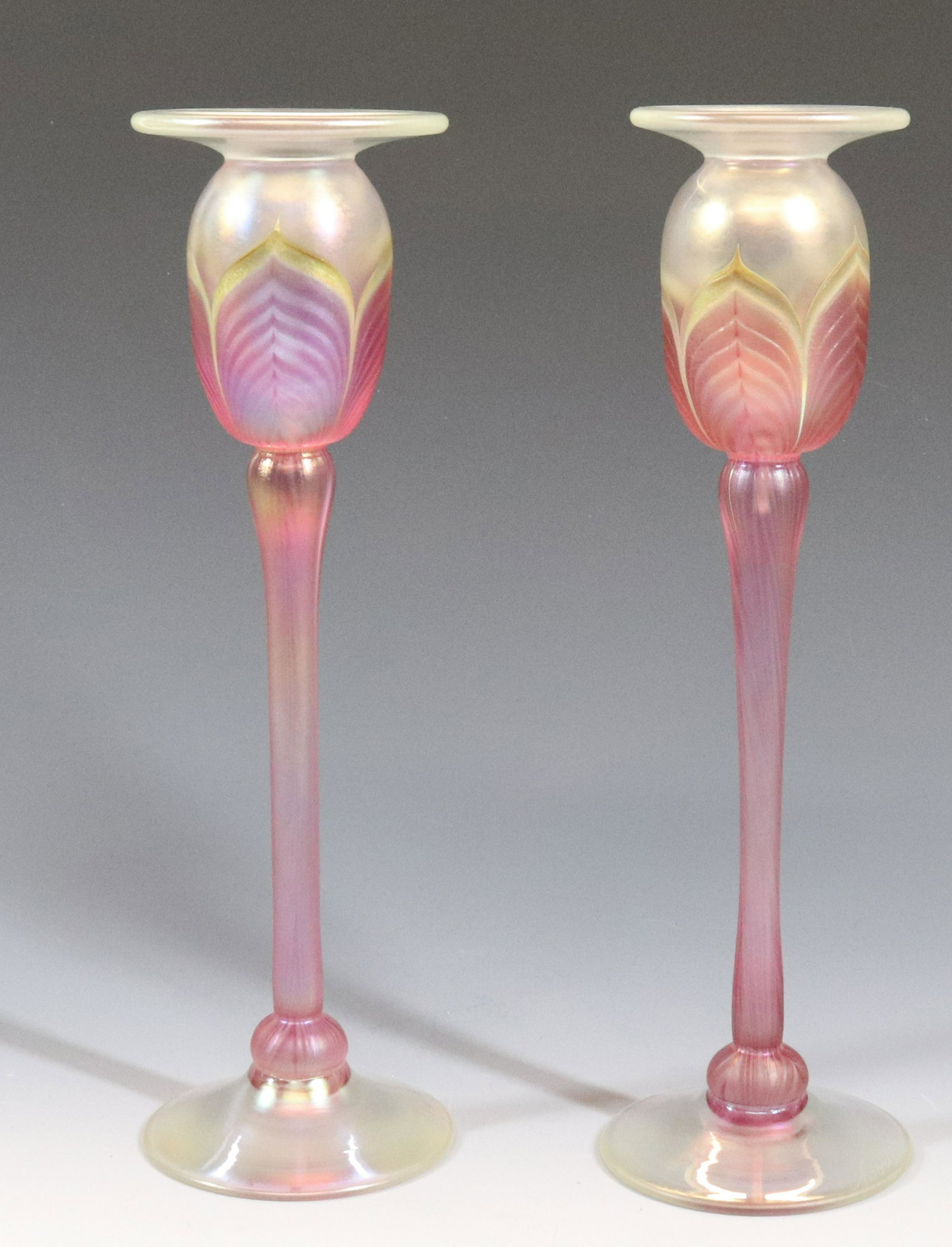 SCOTT CARLSON ART GLASS CANDLESTICKS: PAIR OF CANDLESTICKS IRIDESCENT WITH PINK FEATHERING ON TALL STEMS MARKED BASE SCFRCC 58310 10 3/4" X 3"