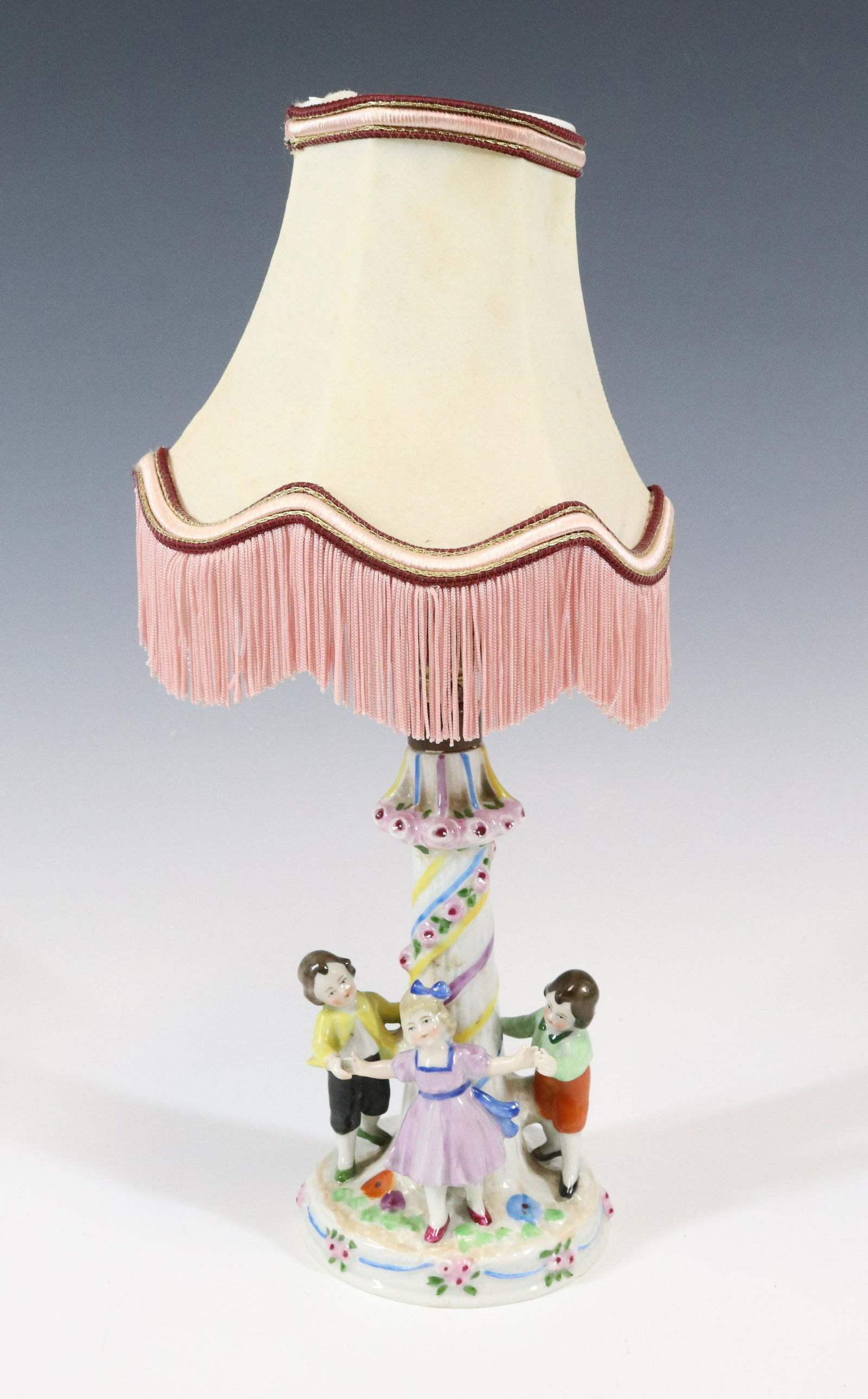 FRENCH PORCELAIN LAMP: THREE CHILDREN PLAYING PINK ROSES FRINGE SHADE AND ORIGINAL FIXTURE UNMARKED 13 1/3" Terms: Please read Carefully before bidding. This is a Two-Part Estate Sale. Pick-up for these sales will be Tuesda