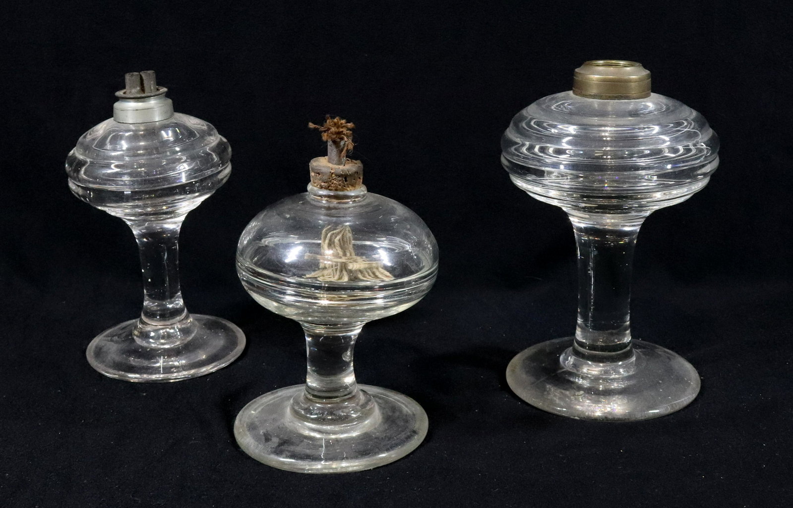 (3) CLEAR GLASS WHALE OIL LAMPS: INCLUDING NEW ENGLAND FREE BLOWN WITH INTERIOR FONT RING IRON PONTIL AND HOMEMADE BURNER. TWO BEEHIVE PATTERN NEW ENGLAND PRESSED WITH HEAVY HORIZONTAL RIBS ONE WITH BURNER. 5" TO 6 1/2"H 3 1/2" TO 4"