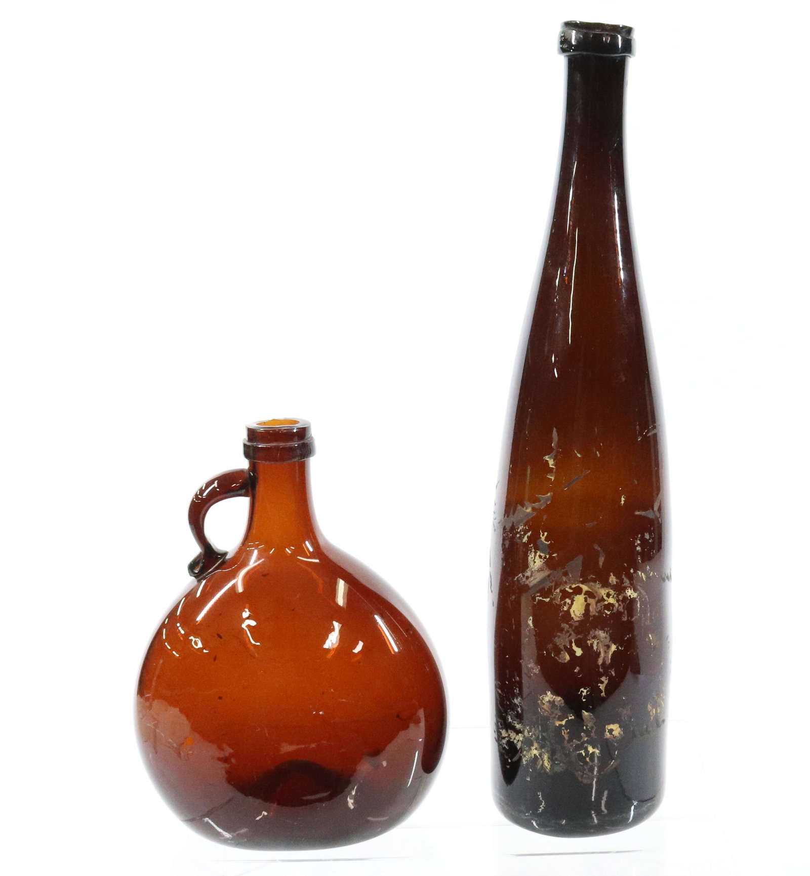 AMBER LIQUOR AND WINE BOTTLE: LIQUOR BOTTLE WITH APPLIED HANDLE (7 1/4" H) AND AMBER WINE WITH REMNANTS OF PAINT DECORATION (13 3/8" H). UPDATED 2023 Terms for Purchasing and Shipping of Auction Items. Please read carefully before