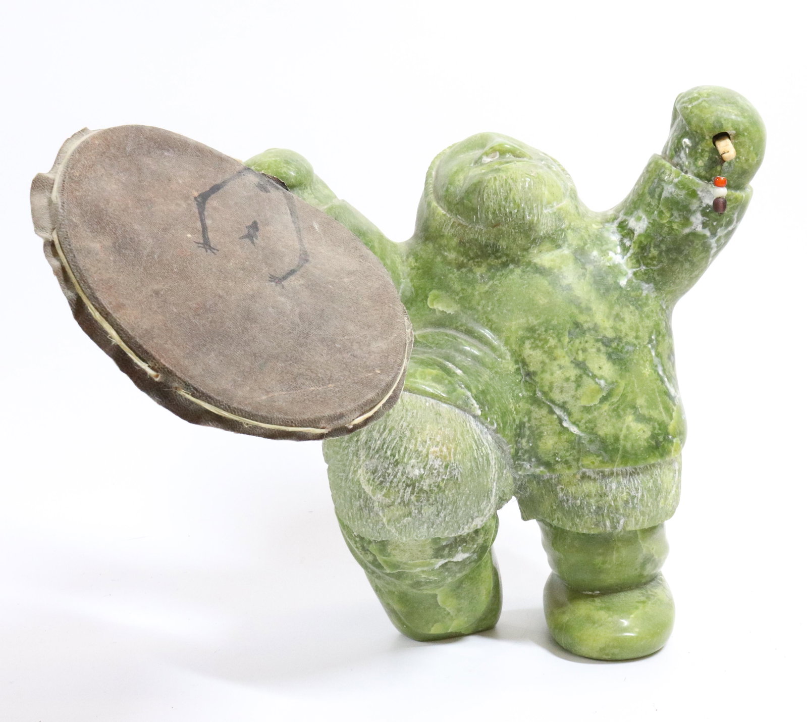 CARVED STONE ESKIMO ART: ESKIMO HOLDING DRUM AND CLUB. LABEL ON BOTTOM OF FOOT "CANADA". INCISED NUMBERS ON BOTTOM. 11" H. UPDATED 2023 TERMS FOR PURCHASING AND SHIPPING OF AUCTION ITEMS. PLEASE READ CAREFULLY BEFORE BIDDING.