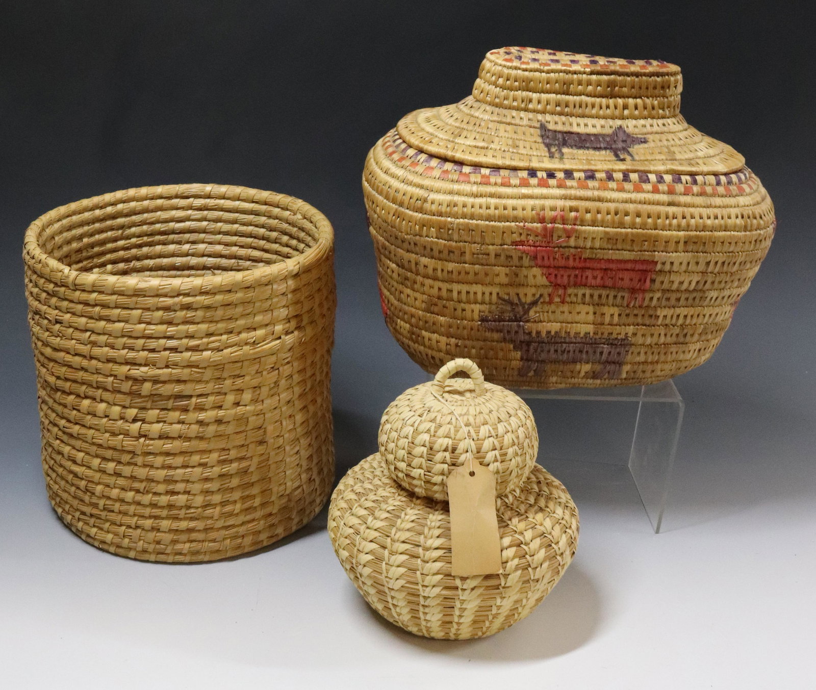 LOT OF BASKETS: (3) INCLUDING - OVAL ESKIMO LIDDED BASKET, PAPAGO INDIAN BASKET WITH ORIGINAL TAG, AND CYLINDRICAL WOVEN BASKET - ESKIMO BASKET 12" X 9" UPDATED 2023 TERMS FOR PURCHASING AND SHIPPING OF AUCTION ITEMS
