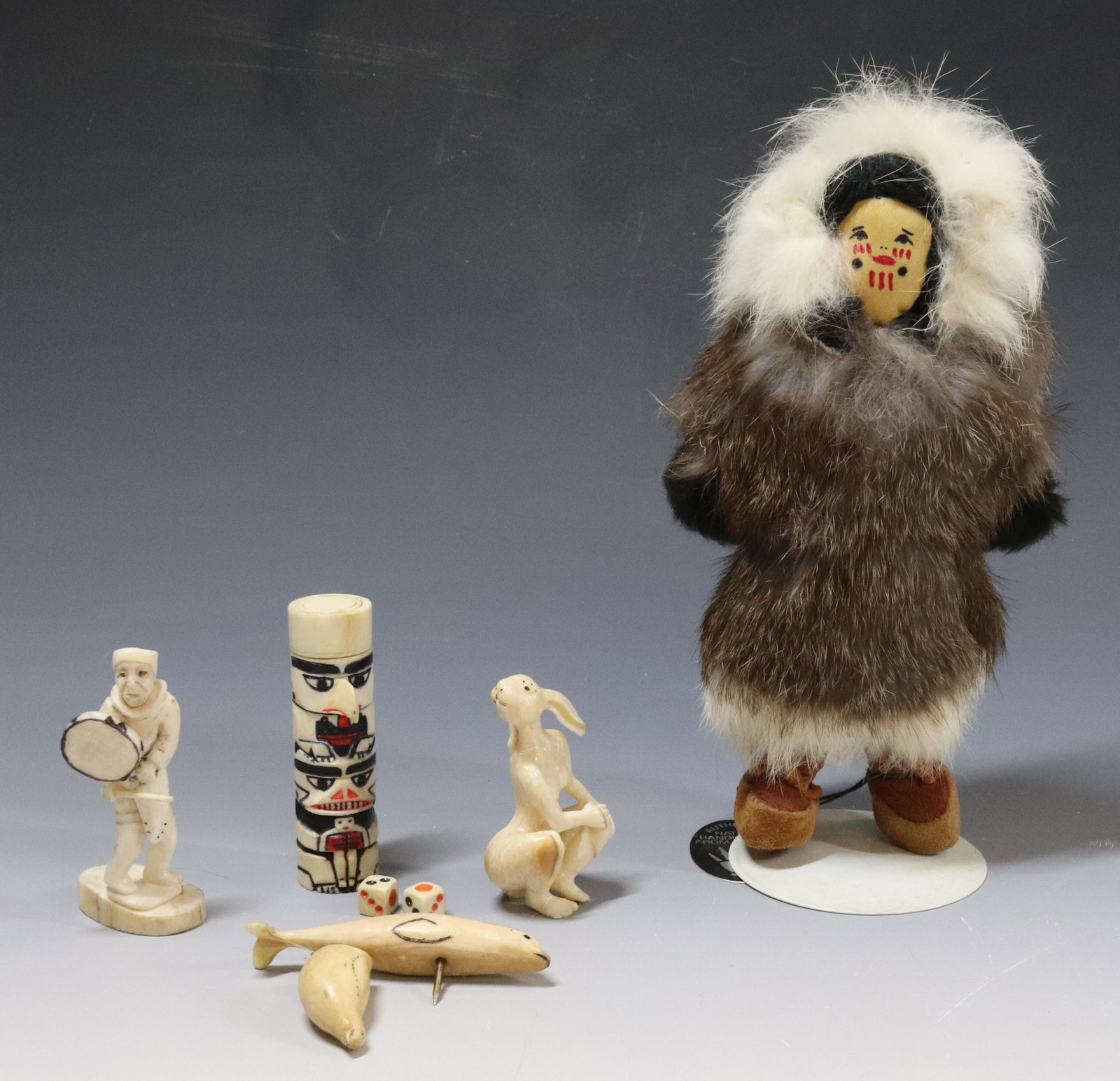 LOT OF INUIT CARVINGS AND DOLL: FUR ESKIMO DOLL AND (5) BONE CARVINGS INCLUDING - TOTEM WITH INTERIOR DICE, SEAL, BIRD, RABBIT/WOMAN, AND MAN WITH DRUM - DOLL HAS ORIGINAL TAG (8"H) UPDATED 2023 TERMS FOR PURCHASING AND SHIPPING OF 