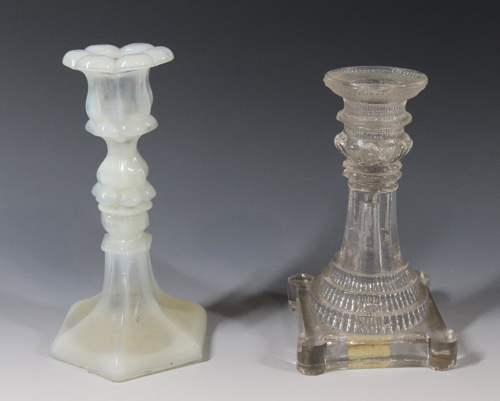 (2) NEW ENGLAND GLASS CANDLESTICKS: OPALESCENT HEXAGONAL BASE PETAL CANDLE CUP AND LACY PERIOD STEPPED BASE WITH LACY CANDLE CUP BOTH WAFER STEMS 7 3/8" X 3 1/2" 6 3/4" X 3 7/8" Please Read Carefully before Bidding. Hartzell’s Auc