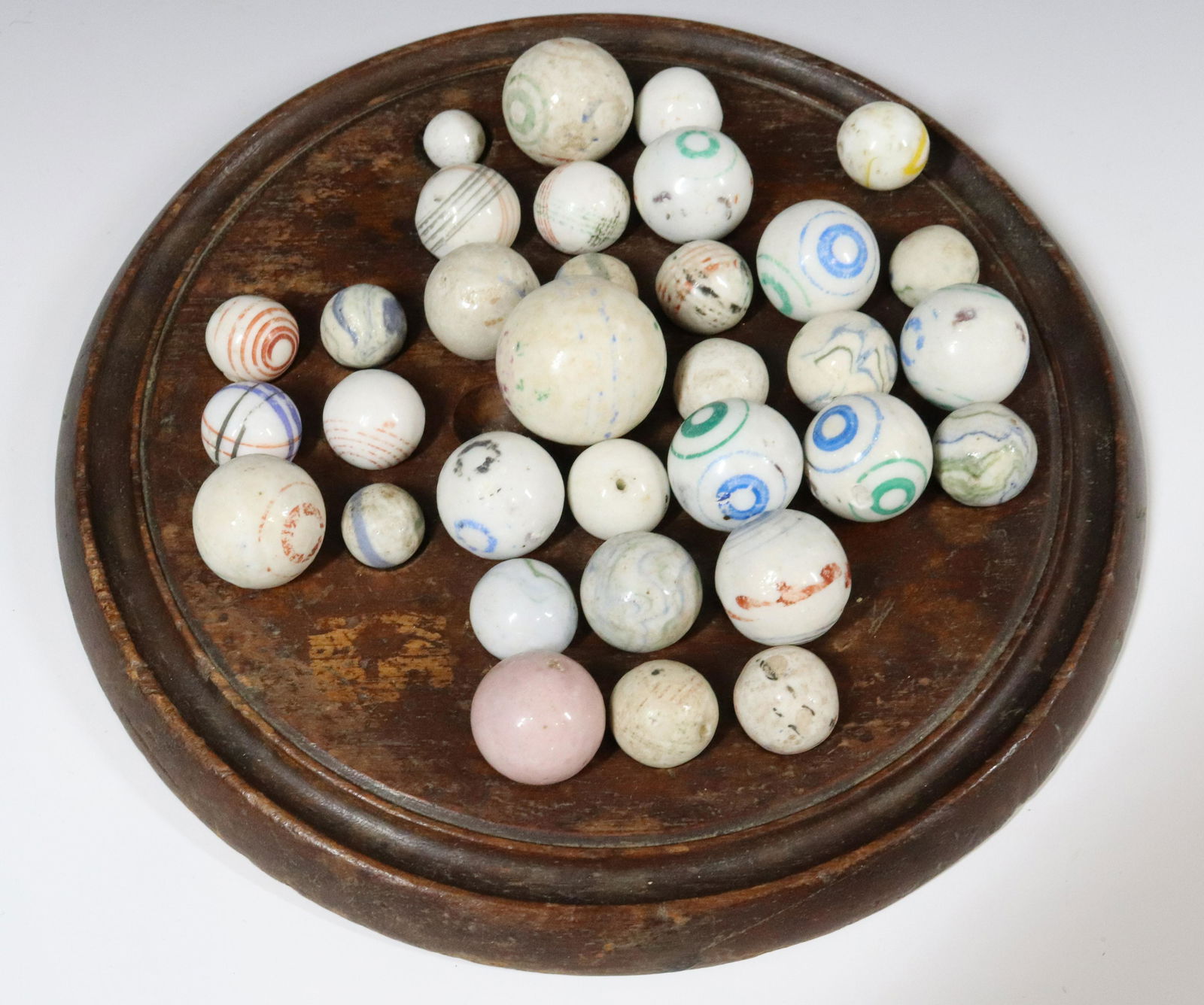 LOT OF PORCELAIN MARBLES ON WOODEN GAME BASE: VARIOUS SIZE AND DESIGNS - BASE 7 1/2" D Please Read Carefully before Bidding. Hartzell’s Auction Gallery Inc. will Conduct an ON-SITE and also ON-LINE Auction at 2481 Belvidere Rd, Phillipsburg