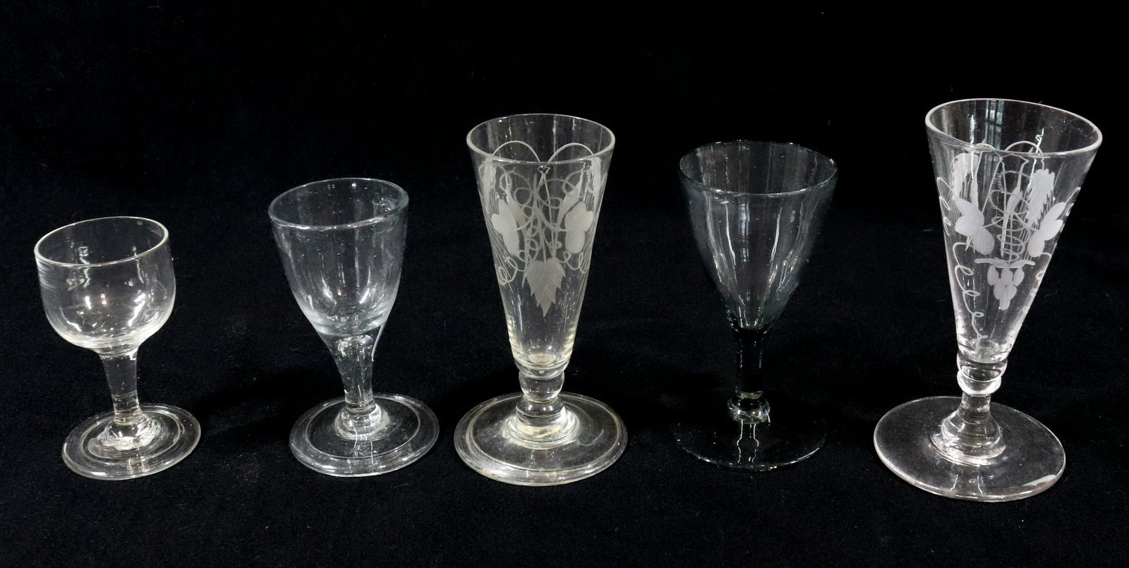(5) FREE BLOWN WINE GLASSES: TWO WITH ENGRAVING AND DOUBLE KNOP STEM ONE SMOKEY CLEAR COLOR, THREE WITH FOLDED RIMS PONTIL SCARS 3 1/2" TO 5 1/2" Please Read Carefully before Bidding. Hartzell’s Auction Gallery Inc. will Co