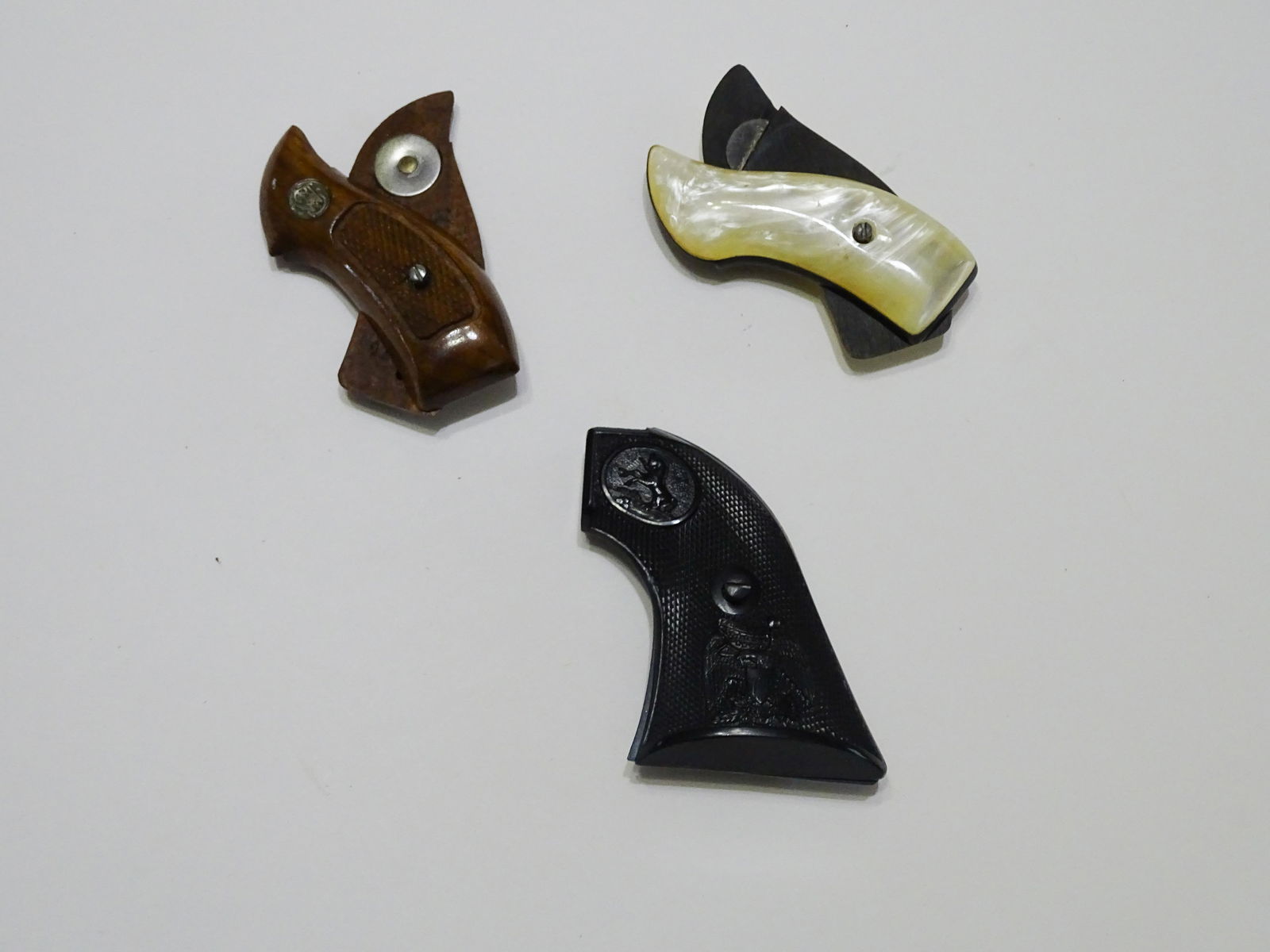 (3) PAIR REVOLVER GRIPS: BLACK BAKELITE COLT WITH EAGLE/FLAG, WINCHESTER WALNUT WITH BUTTON AND FAUX MOTHER OF PEARL WITH BLACK BAKELITE 3 1/2" UPDATED 2023 Terms for Purchasing and Shipping of Auction Items. Please read care