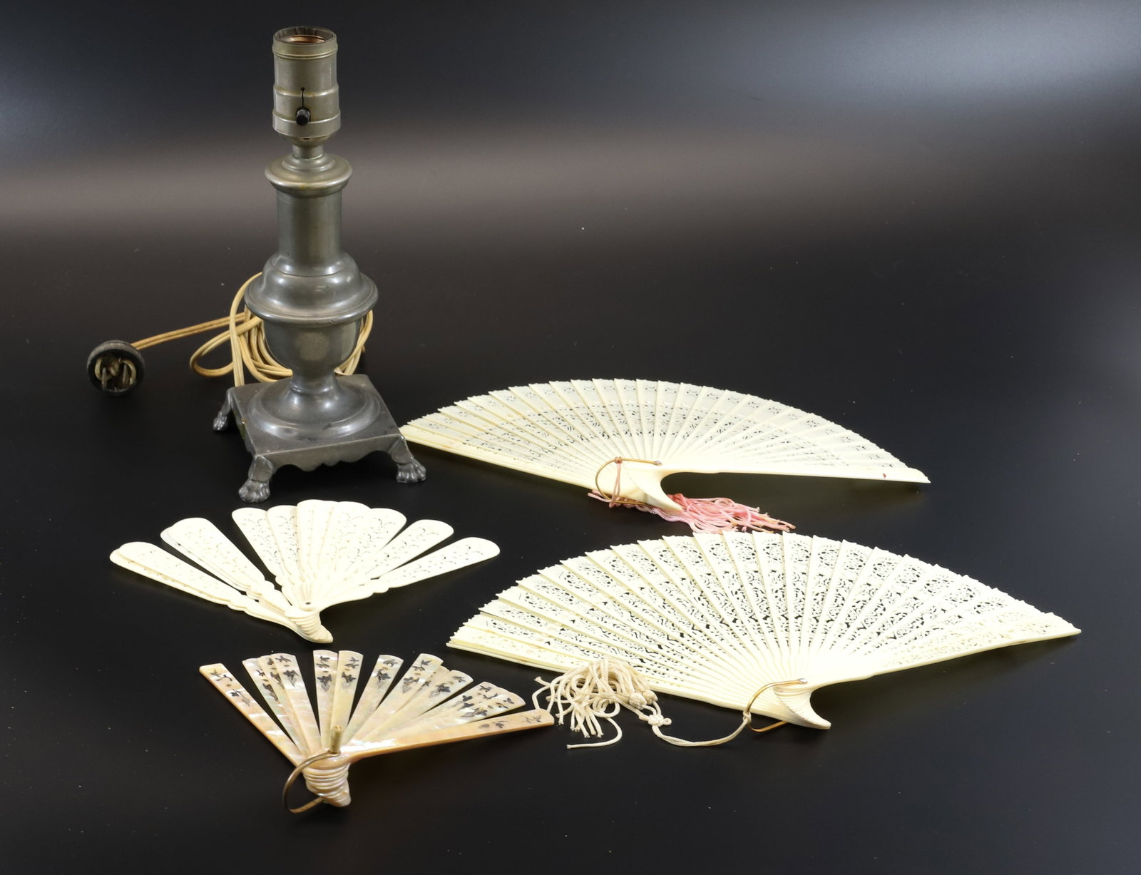 LOT OF CELLULOID FANS AND PEWTER LAMP: FOUR CUT-WORK FANS AND ELECTRIC PEWTER LAMP WITH PAW FEET. 9 1/2" TOTAL HEIGHT. Terms: PLEASE READ CAREFULLY - Terms for Purchasing and Shipping of Auction Items. Please read carefully before bidding.