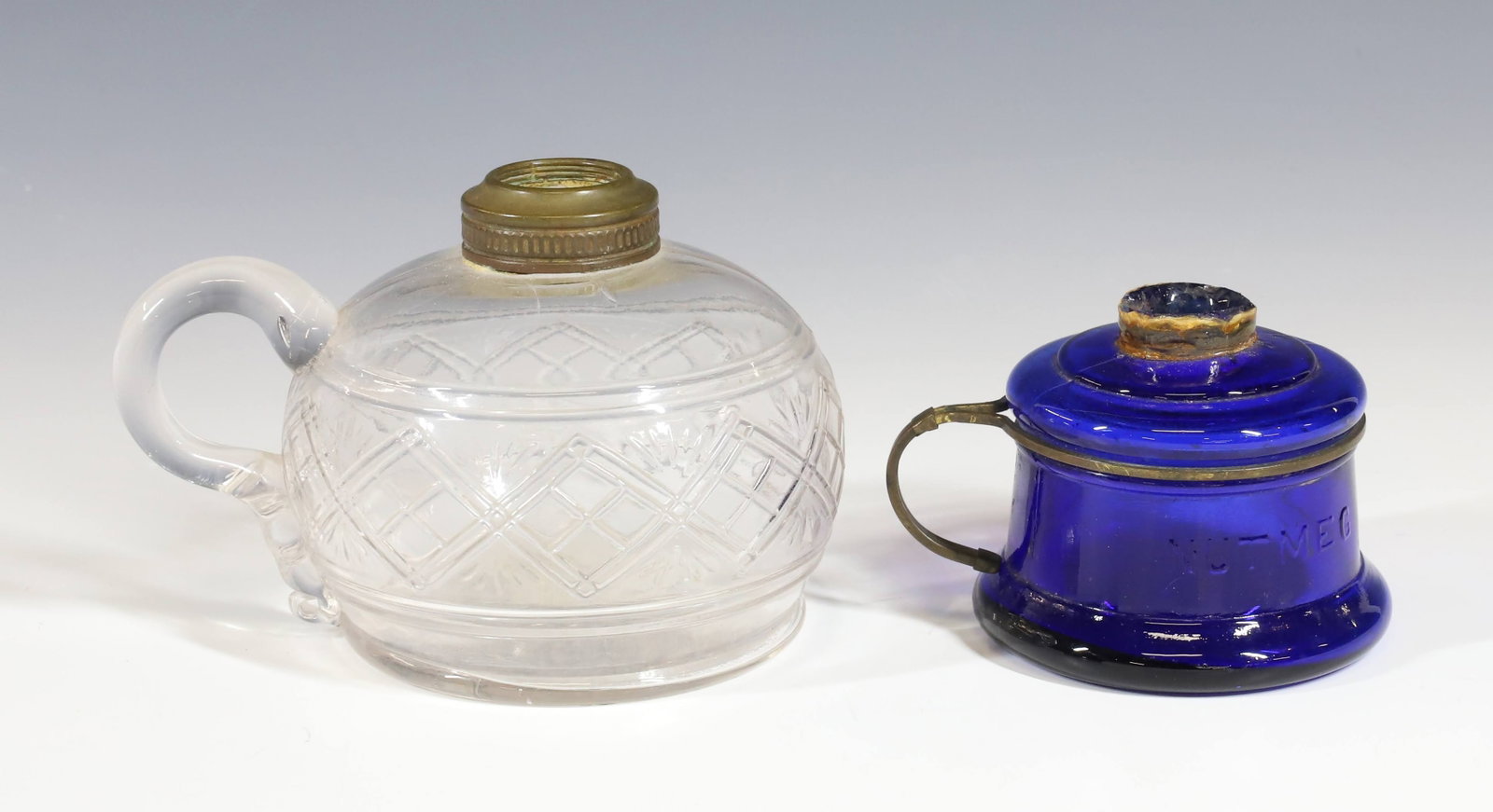 (2) EARLY AMERICAN GLASS LAMPS: CLEAR WITH APPLIED HANDLE DIAMOND AND FAN VARIANT AND COBALT BLUE NUTMEG WITH WIRE HANDLE 3 1/2"H 21/2"H PLEASE READ CAREFULLY - Terms for Purchasing and Shipping of Auction Items. Please read careful